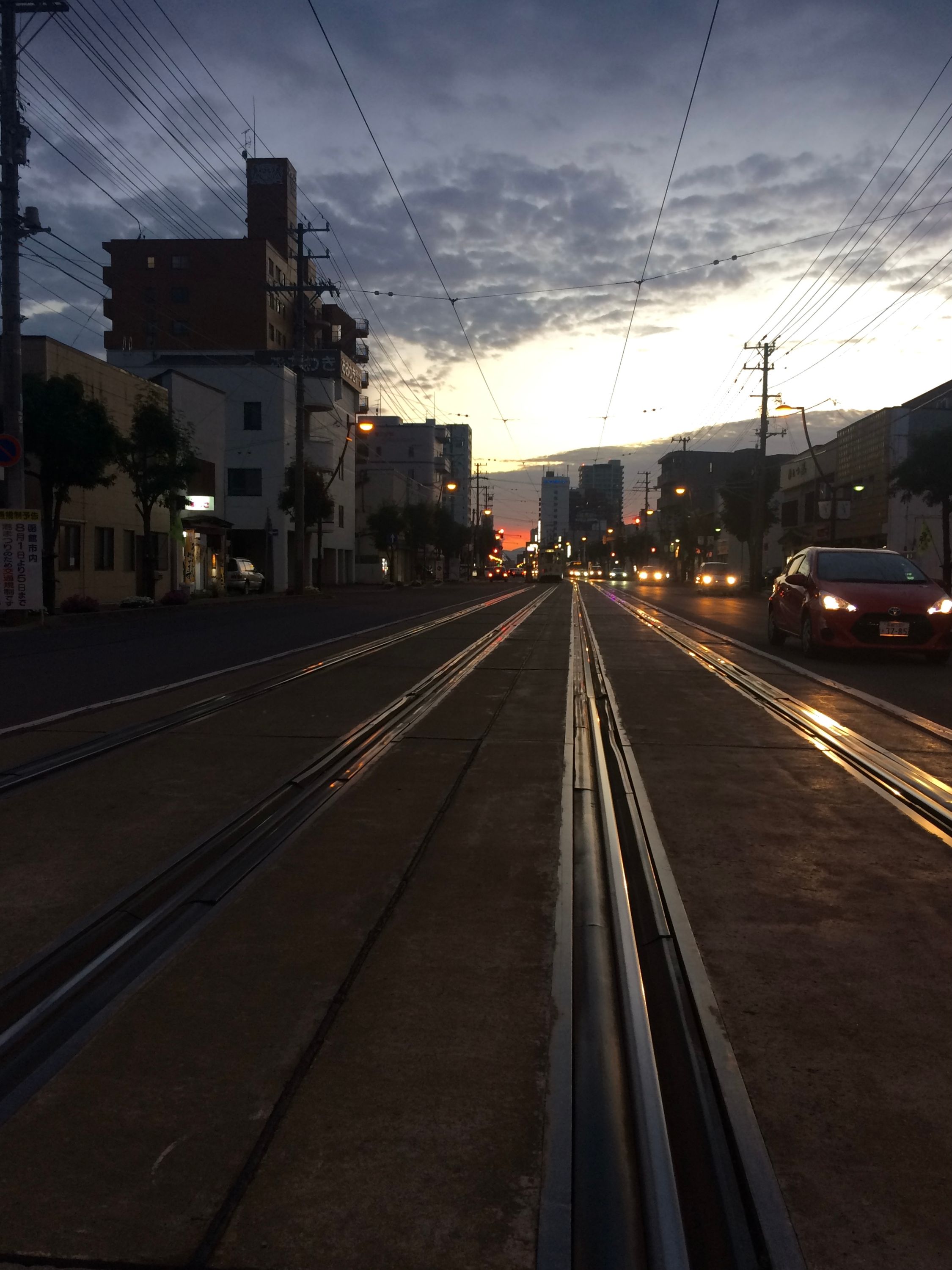 Looking down a street along a tram line in the sunset.