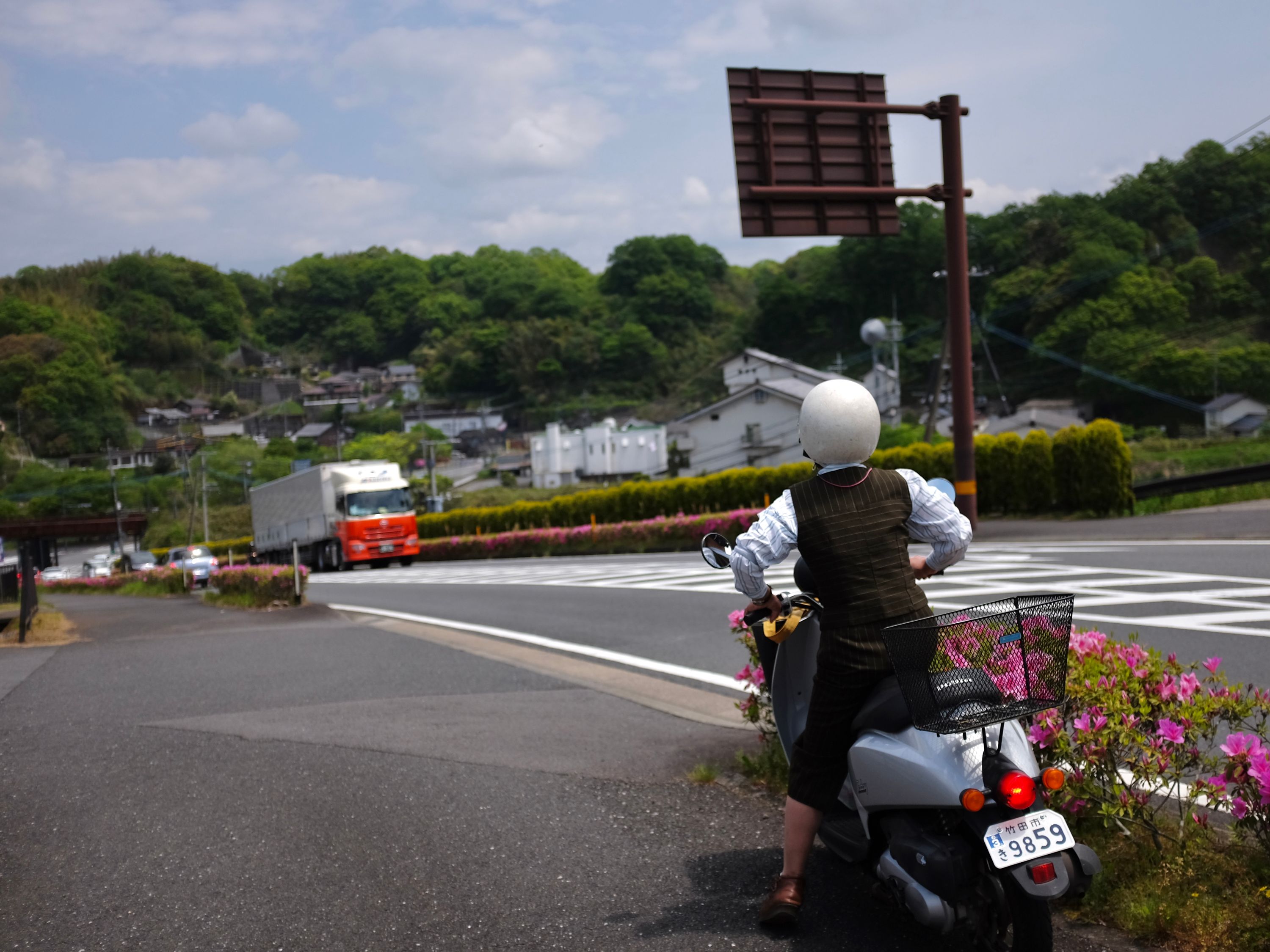 A woman in a stylish European dress mounts a white scooter.