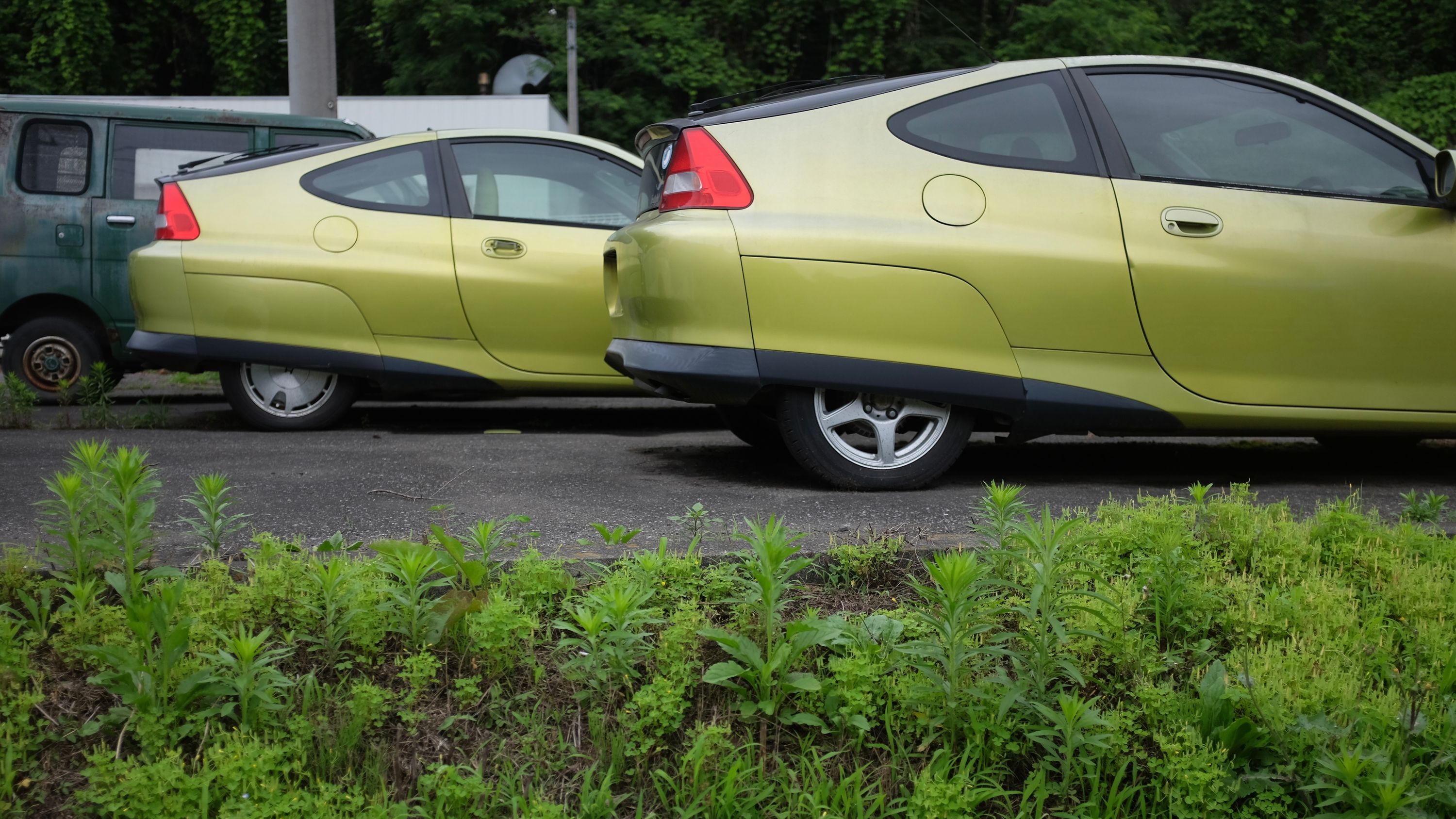 Two lime green first generation Honda Insight hybrid cars in a parking lot.