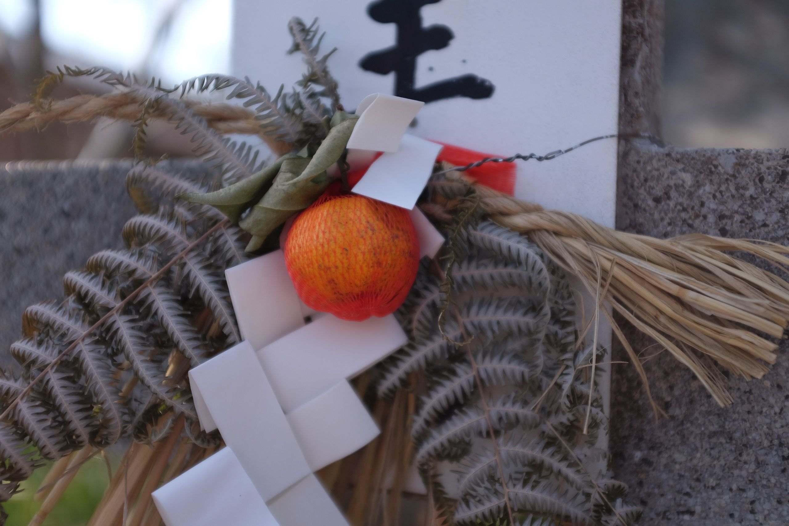 A bouquet at a shrine with an orange in its center.