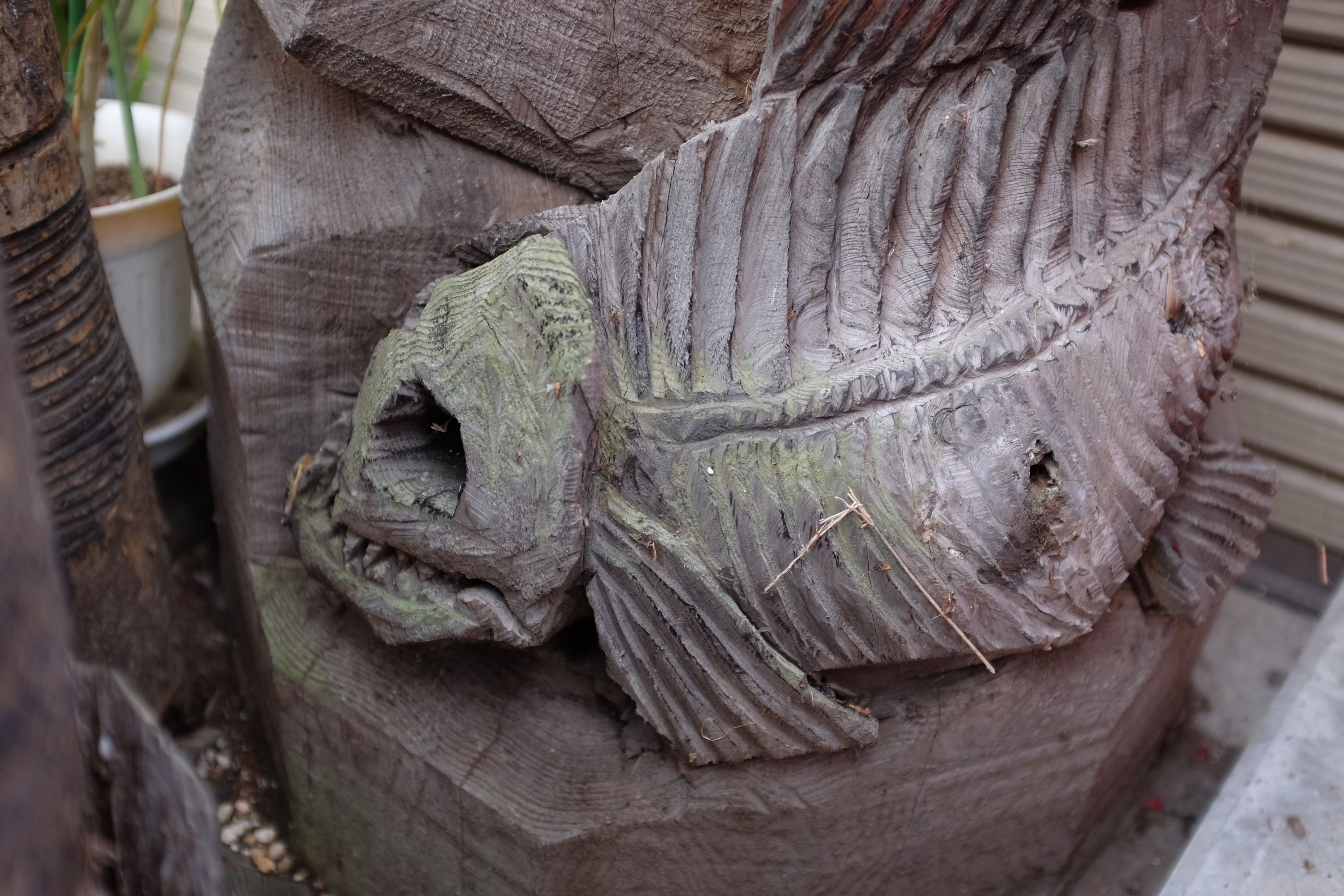 Detail of the statue showing a fish skeleton, also carved in wood.