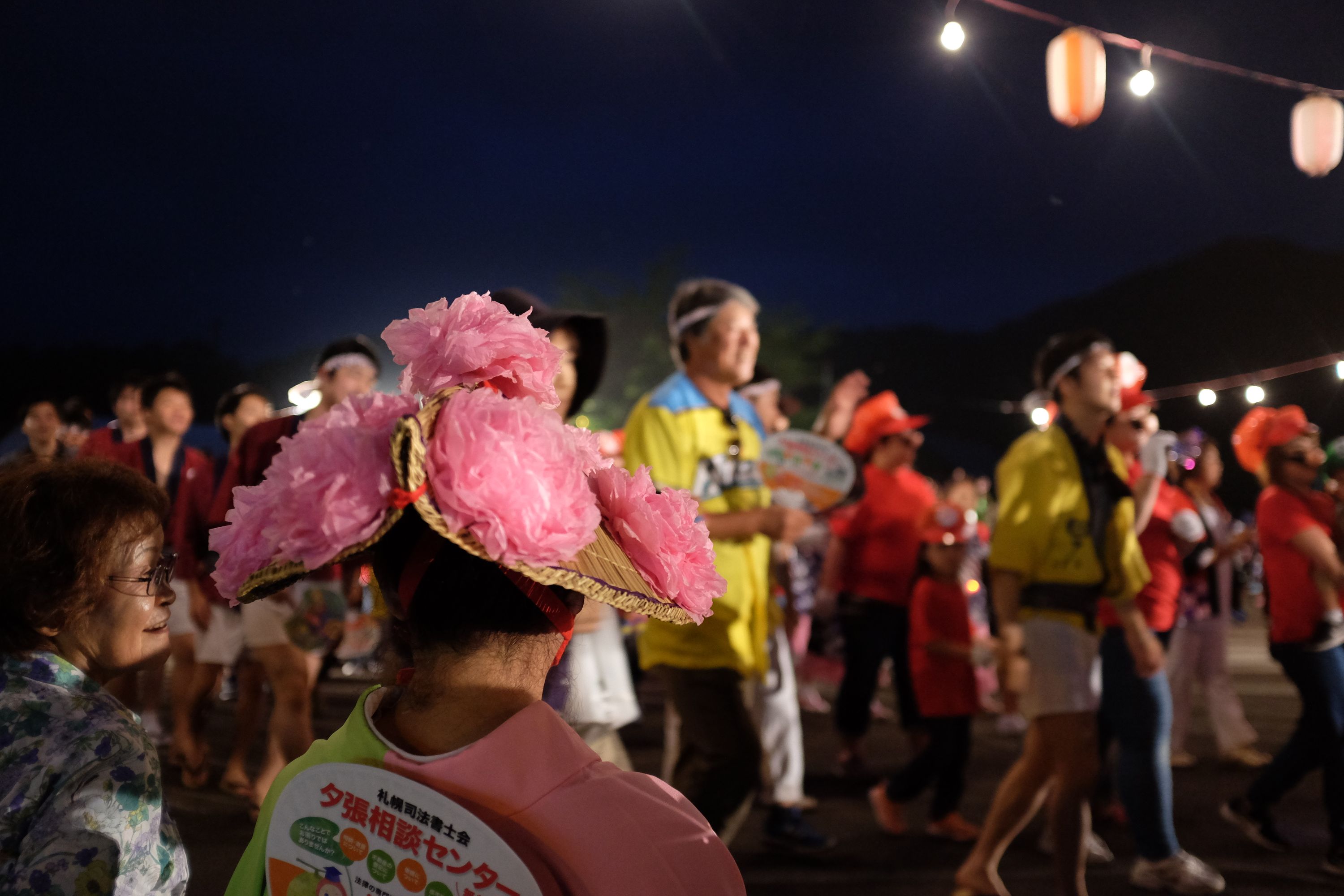 Two women in summer kimonos talk and watch the dancers.