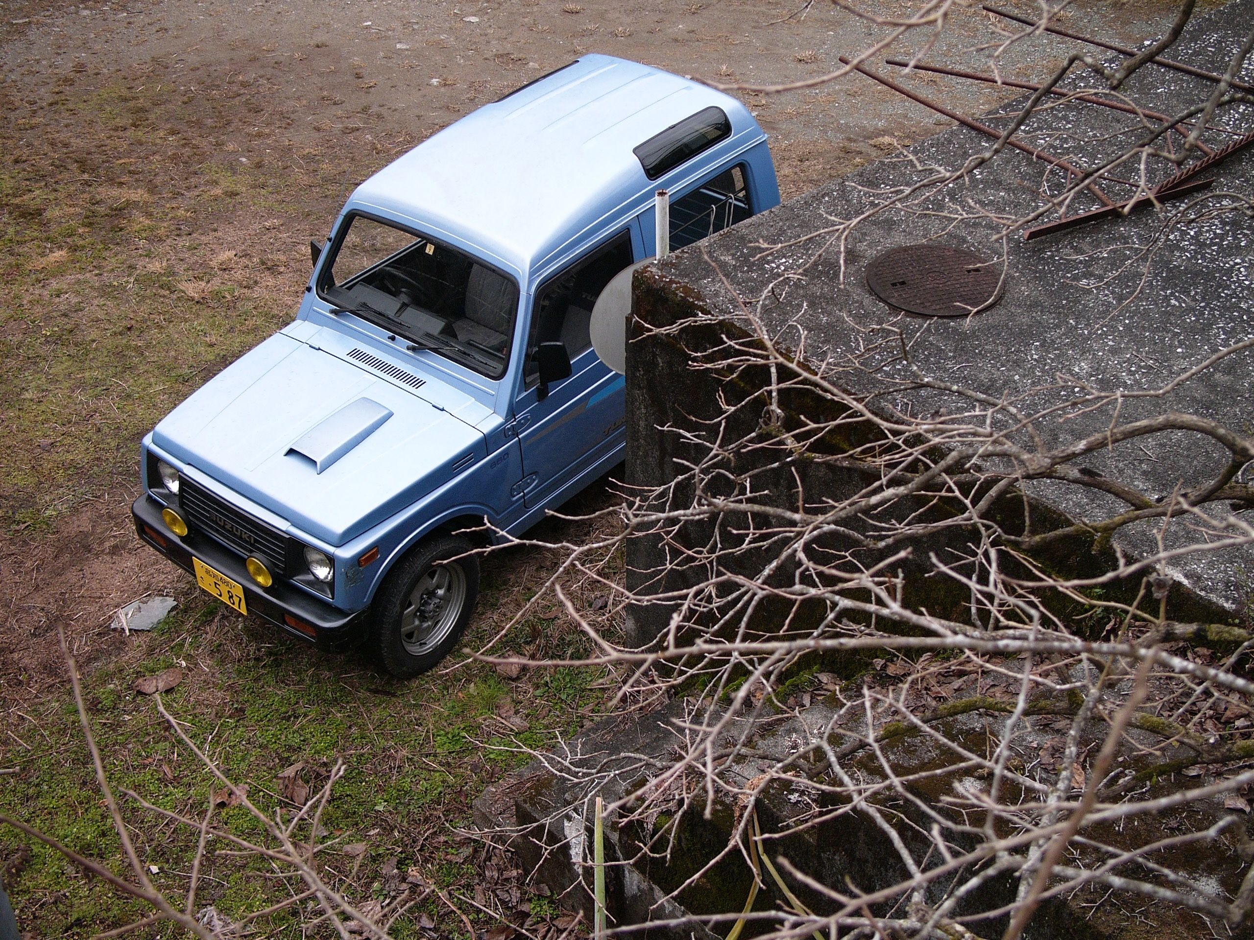 Looking down on an old blue Suzuki Samurai micro-jeep.