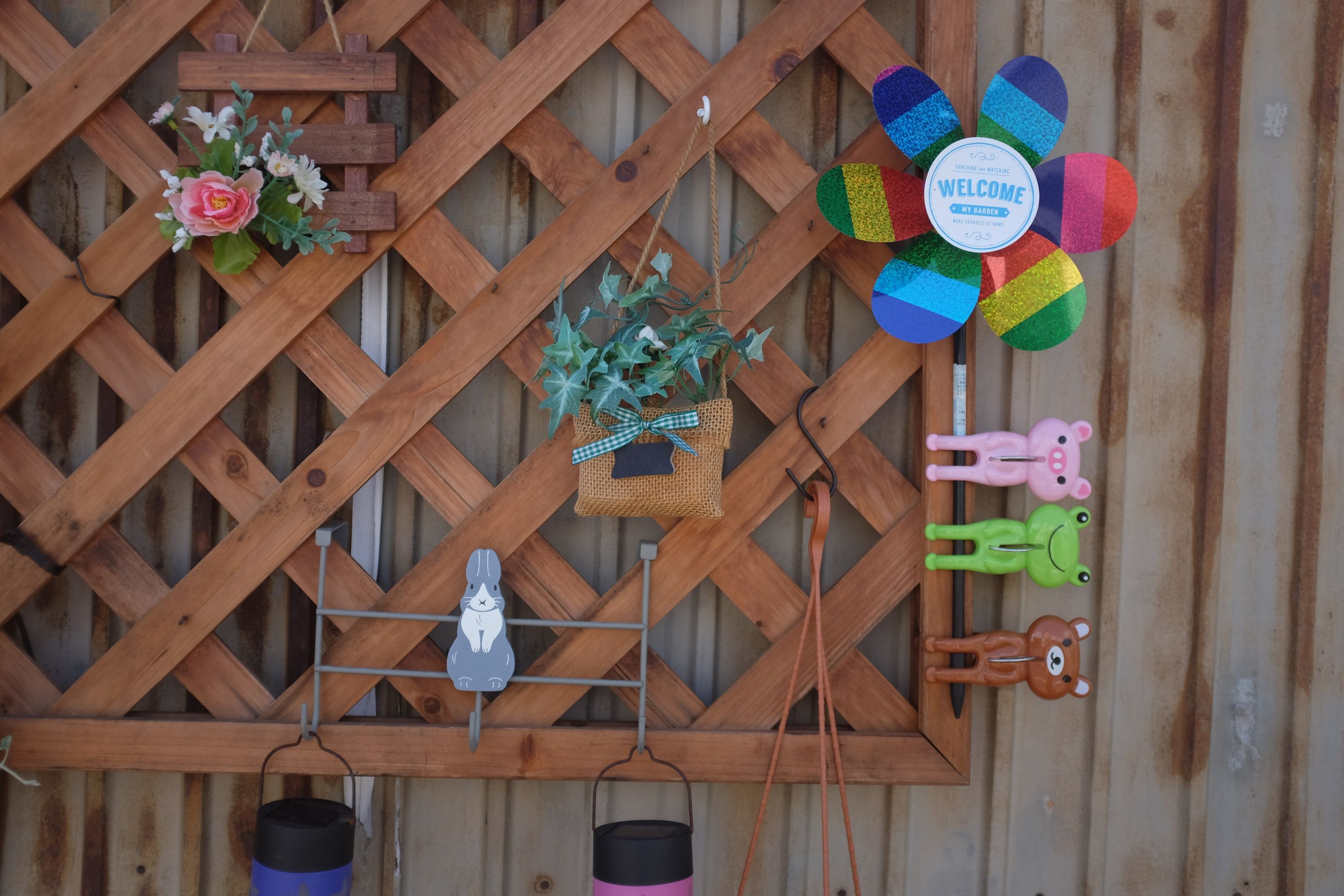 A wooden trellis decorated with various tchotchkes, including three similar-looking plastic animals: a pig, a frog, and a bear.