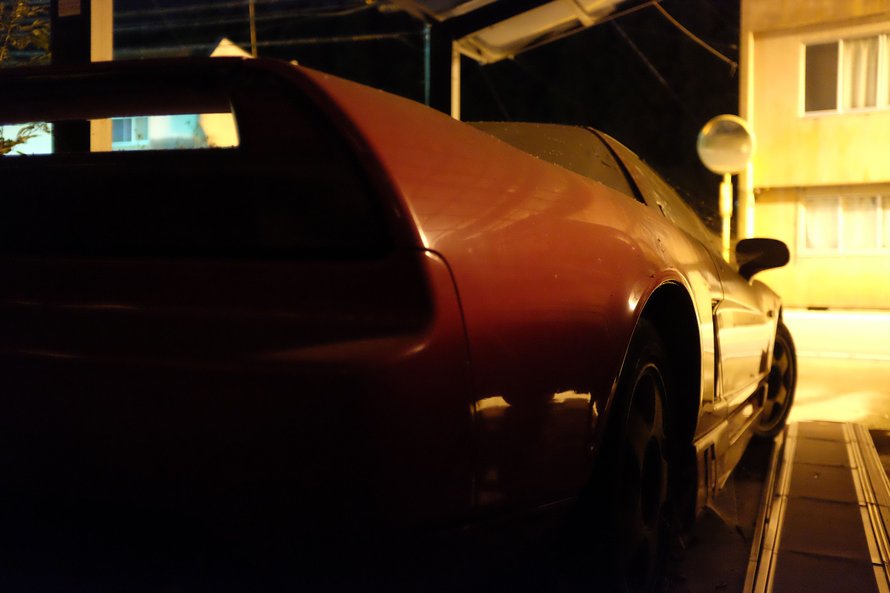 The rear of a Honda NSX, looking out on the street from behind its rear wing.