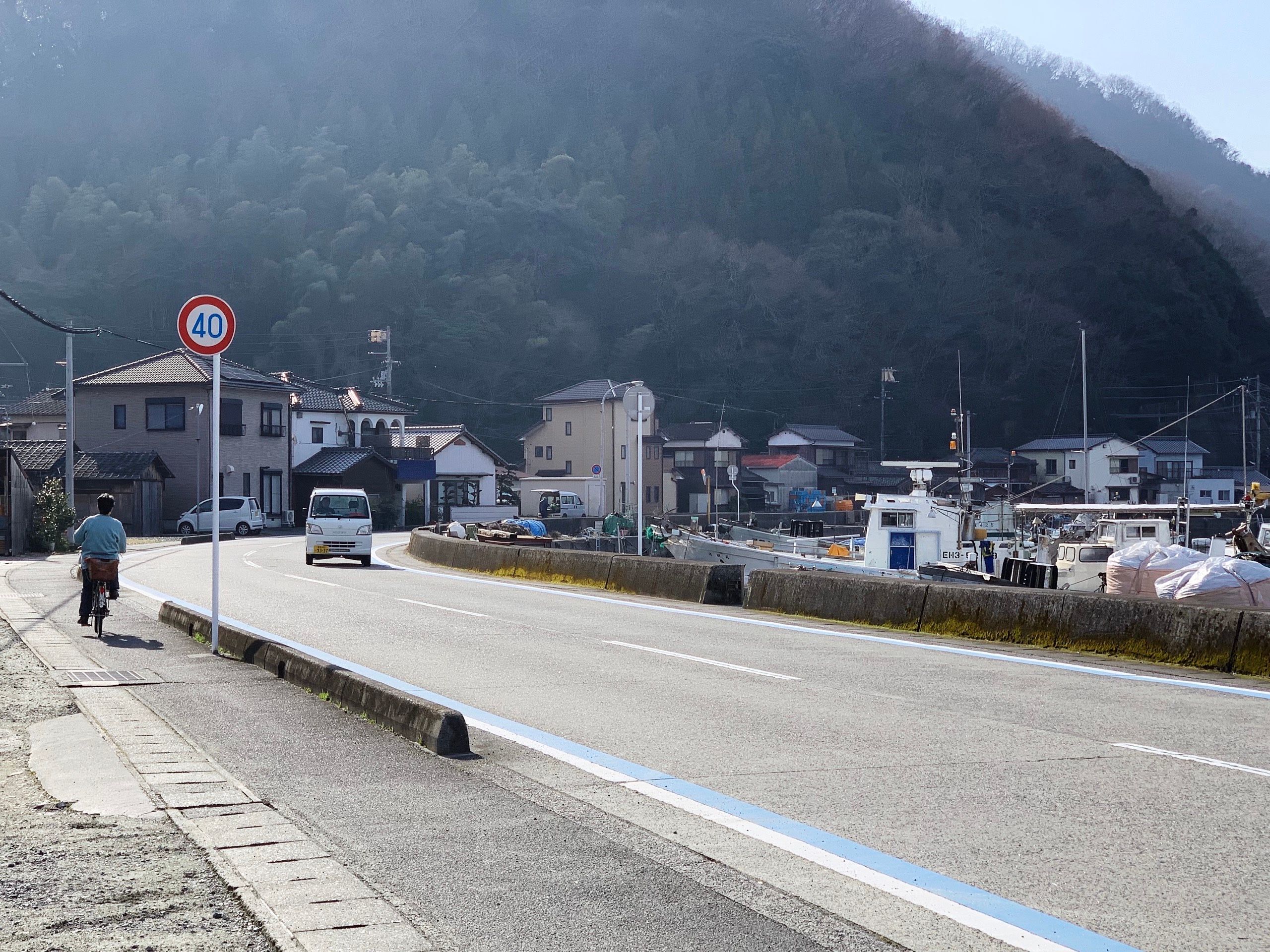 The woman in the picture above cycles away on a road towards a hill.