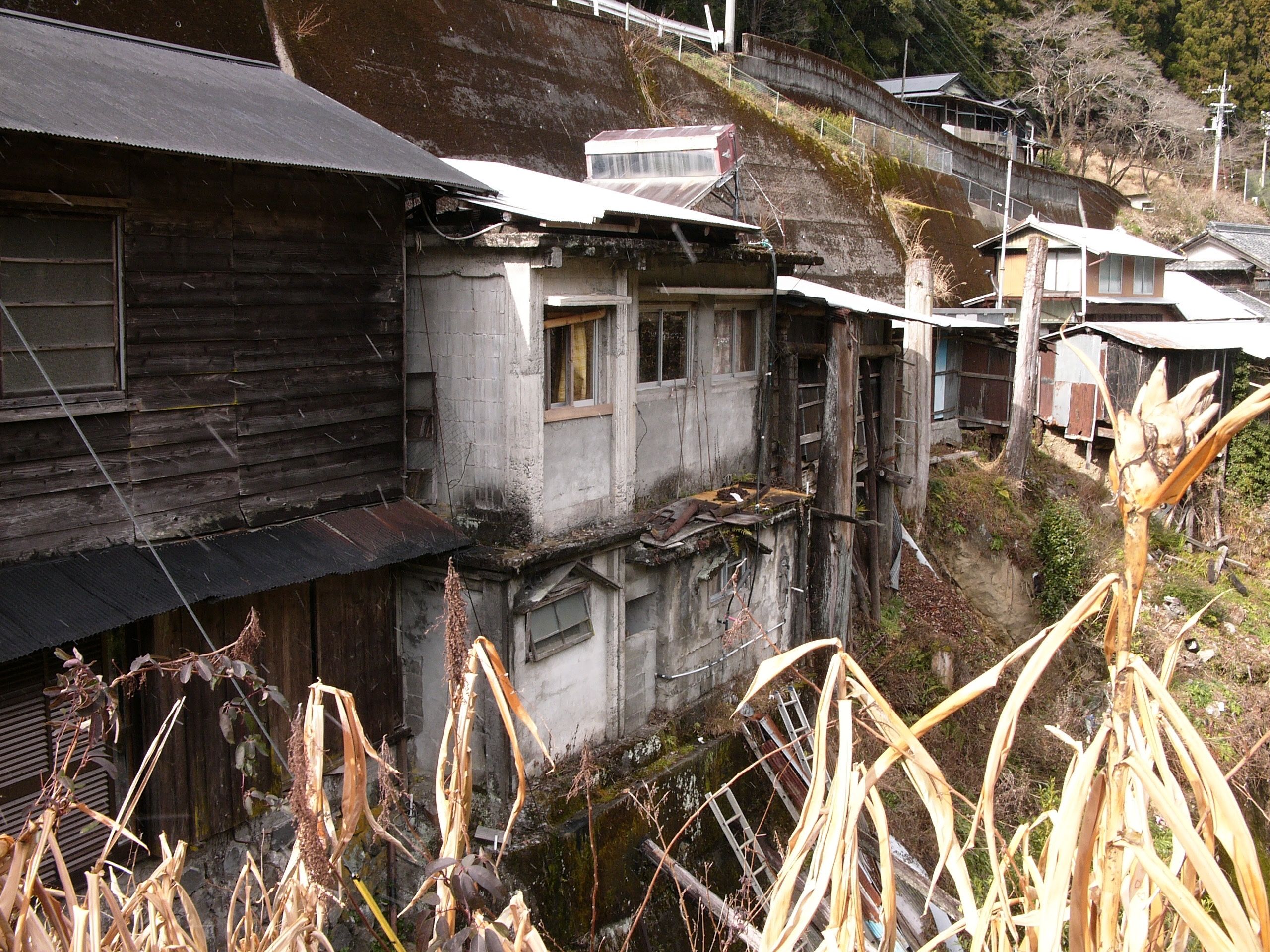 Old, crumbling houses built on the steep bank of a stream.
