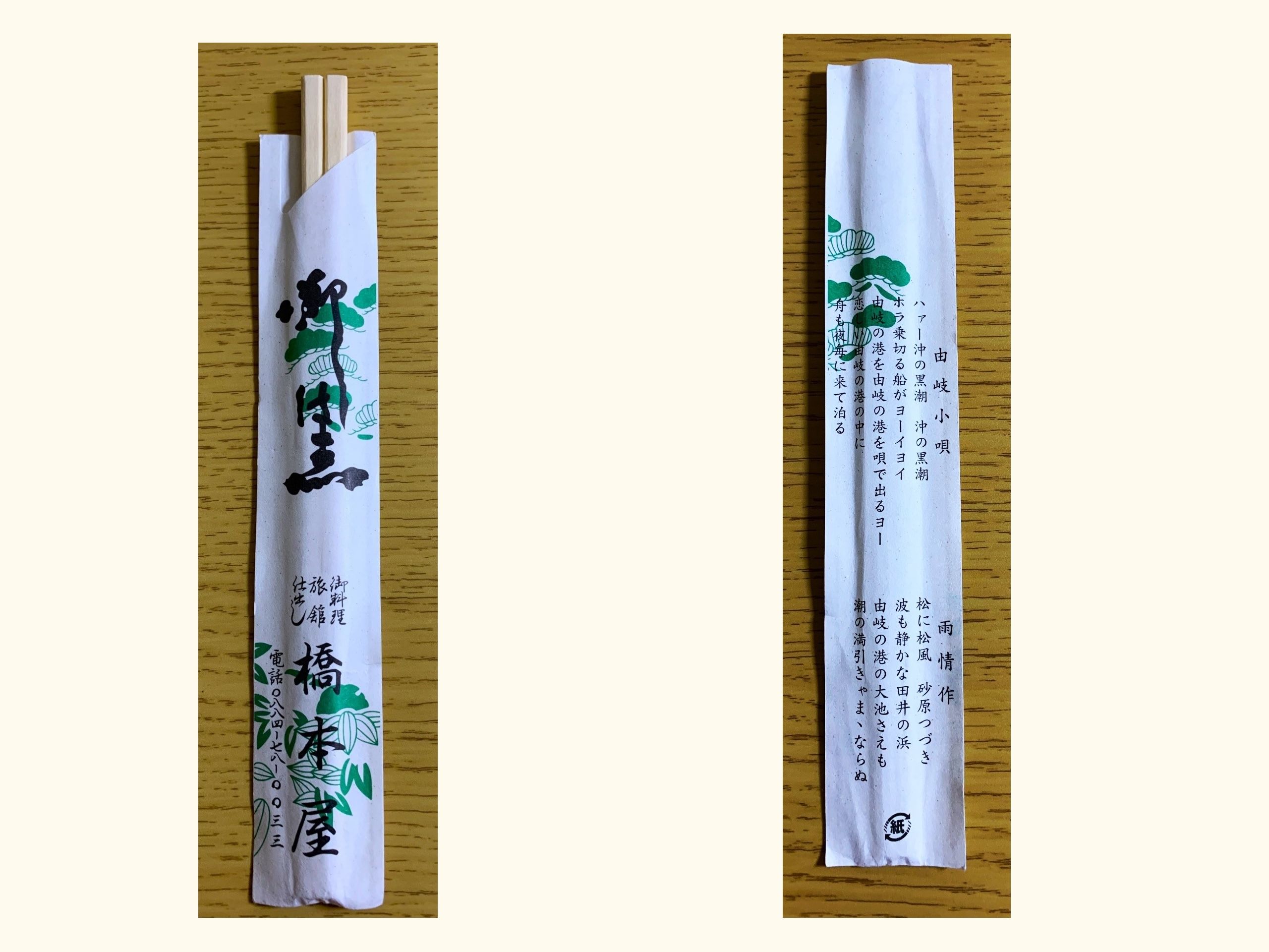 A pair of wooden chopsticks in a white paper wrapper on a light wooden surface. The wrapper features Japanese calligraphy in black ink, including what appears to be “橋本屋” (Hashimotoya). The wrapper is decorated with delicate green illustrations of leaves and foliage scattered around the text. The wooden chopsticks are visible protruding from the top of the wrapper.