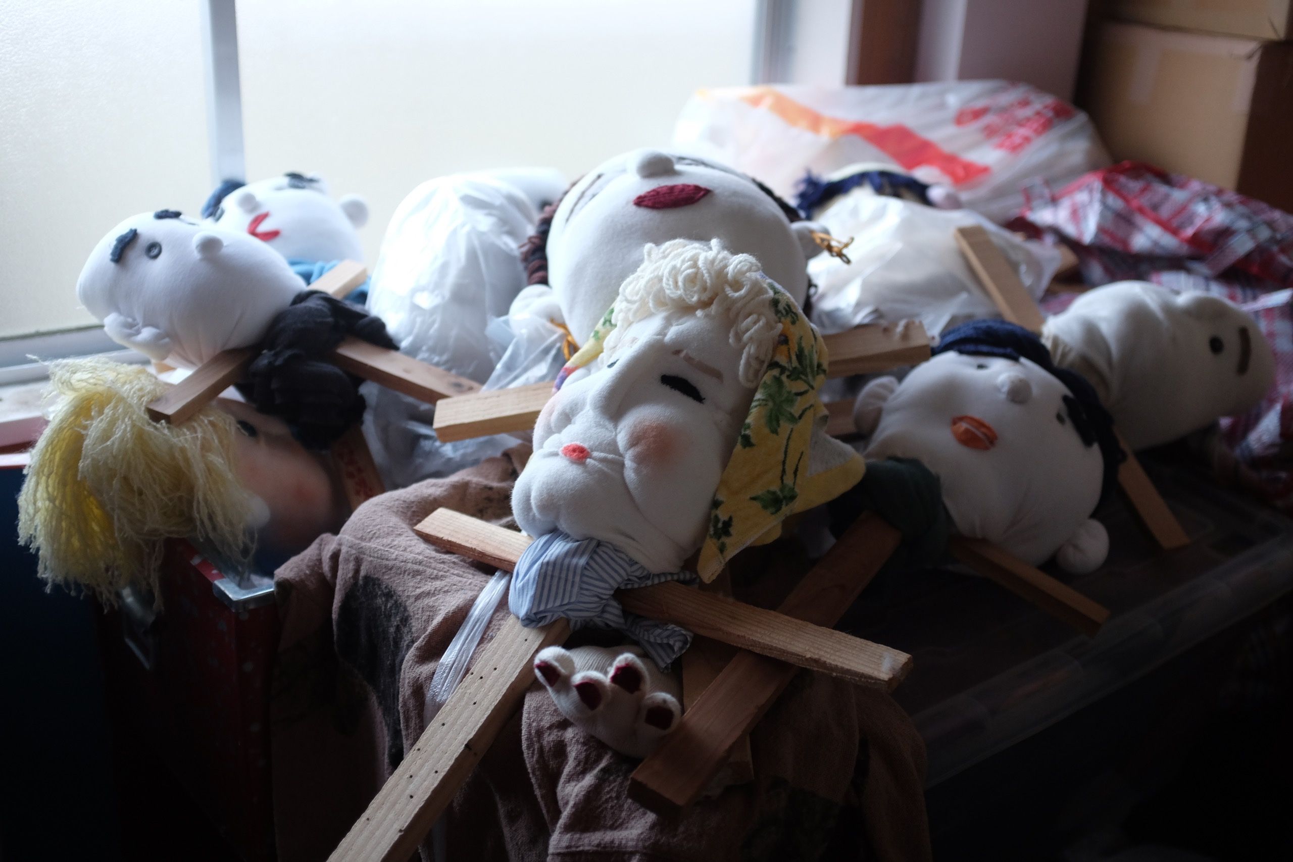 A pile of unfinished doll heads, with wooden supports for shoulders and spines.