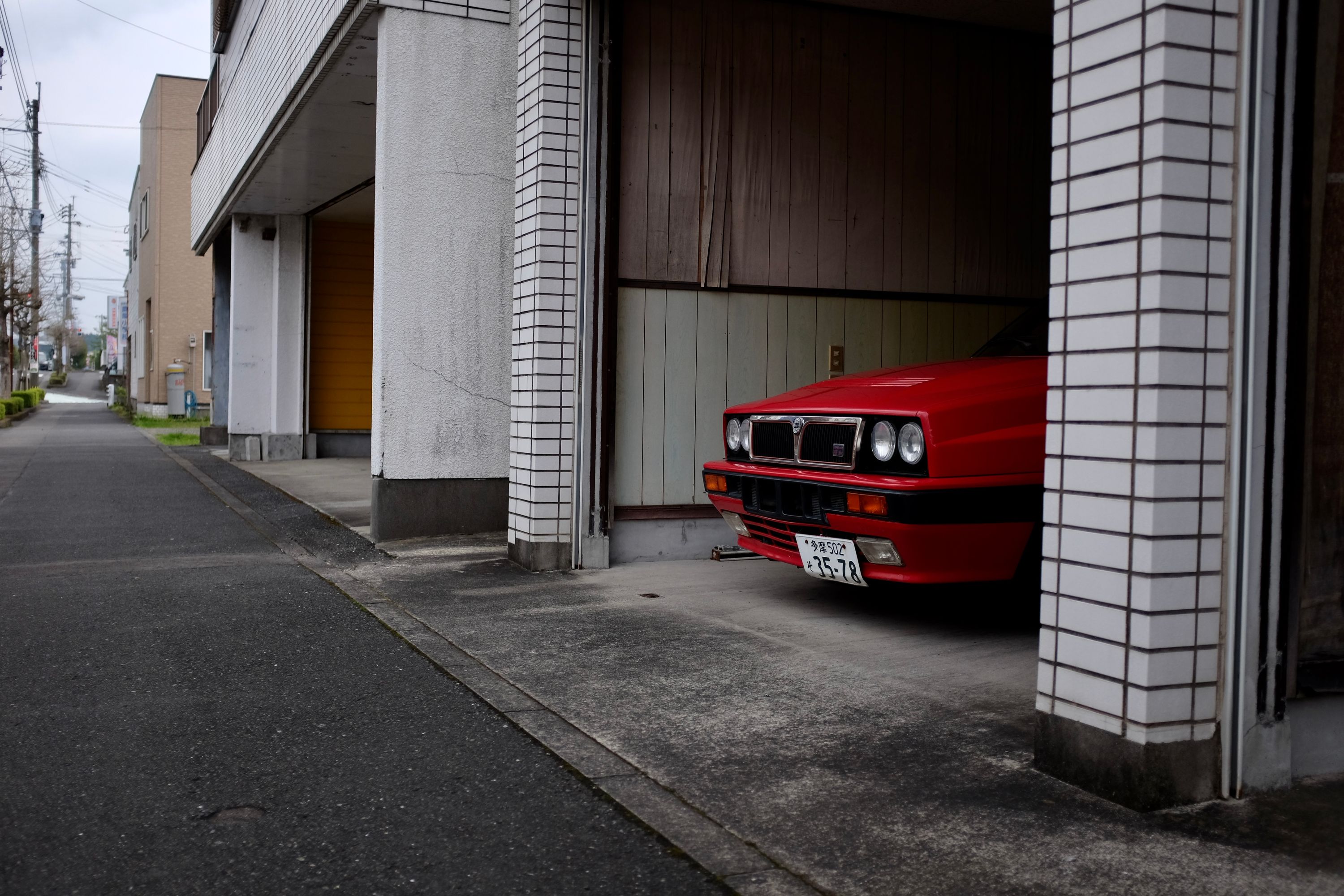 The Lancia peeks out from a row of garages and shops.