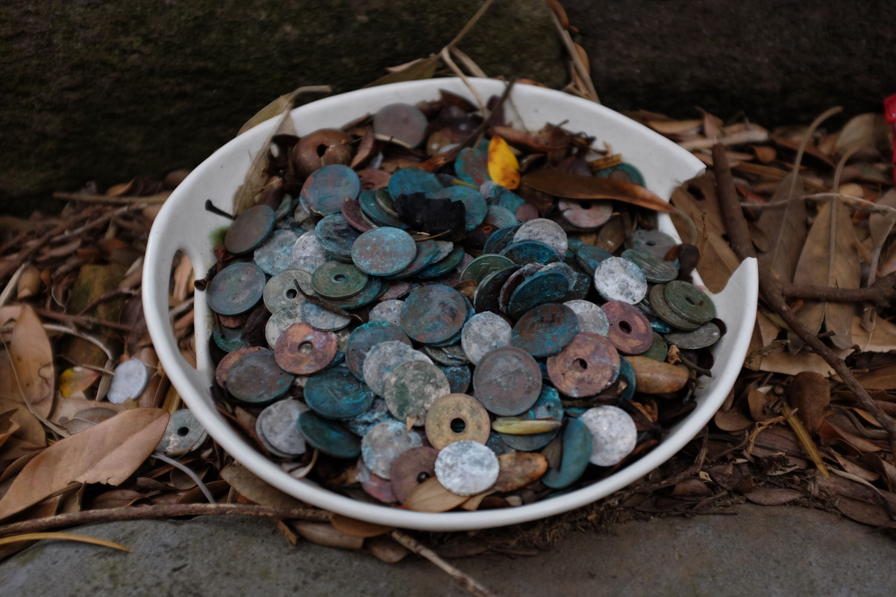 A dish of very old coins at a shrine.
