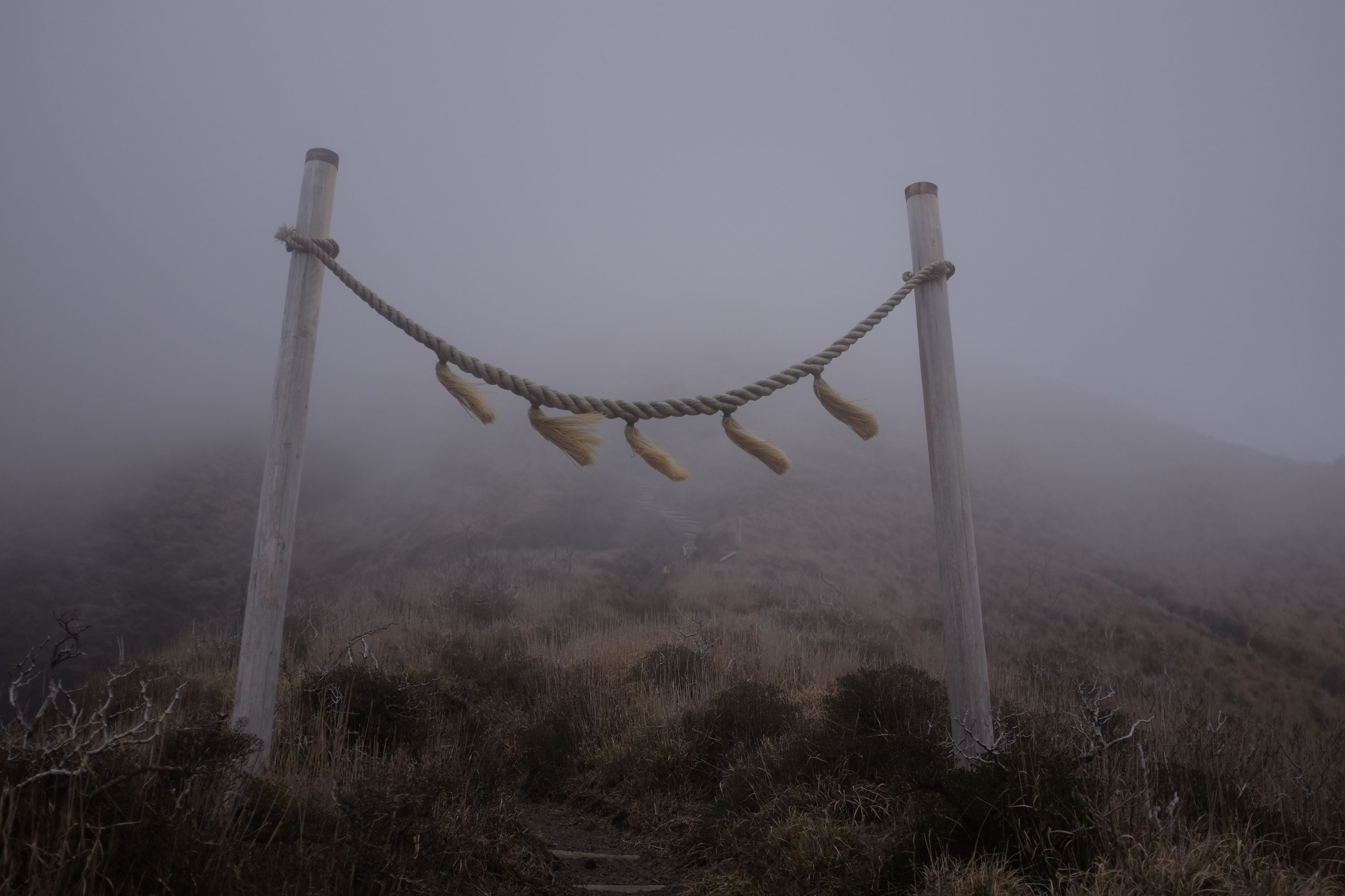 The gate of a Shinto shrine on a windy, cloudy mountainside.
