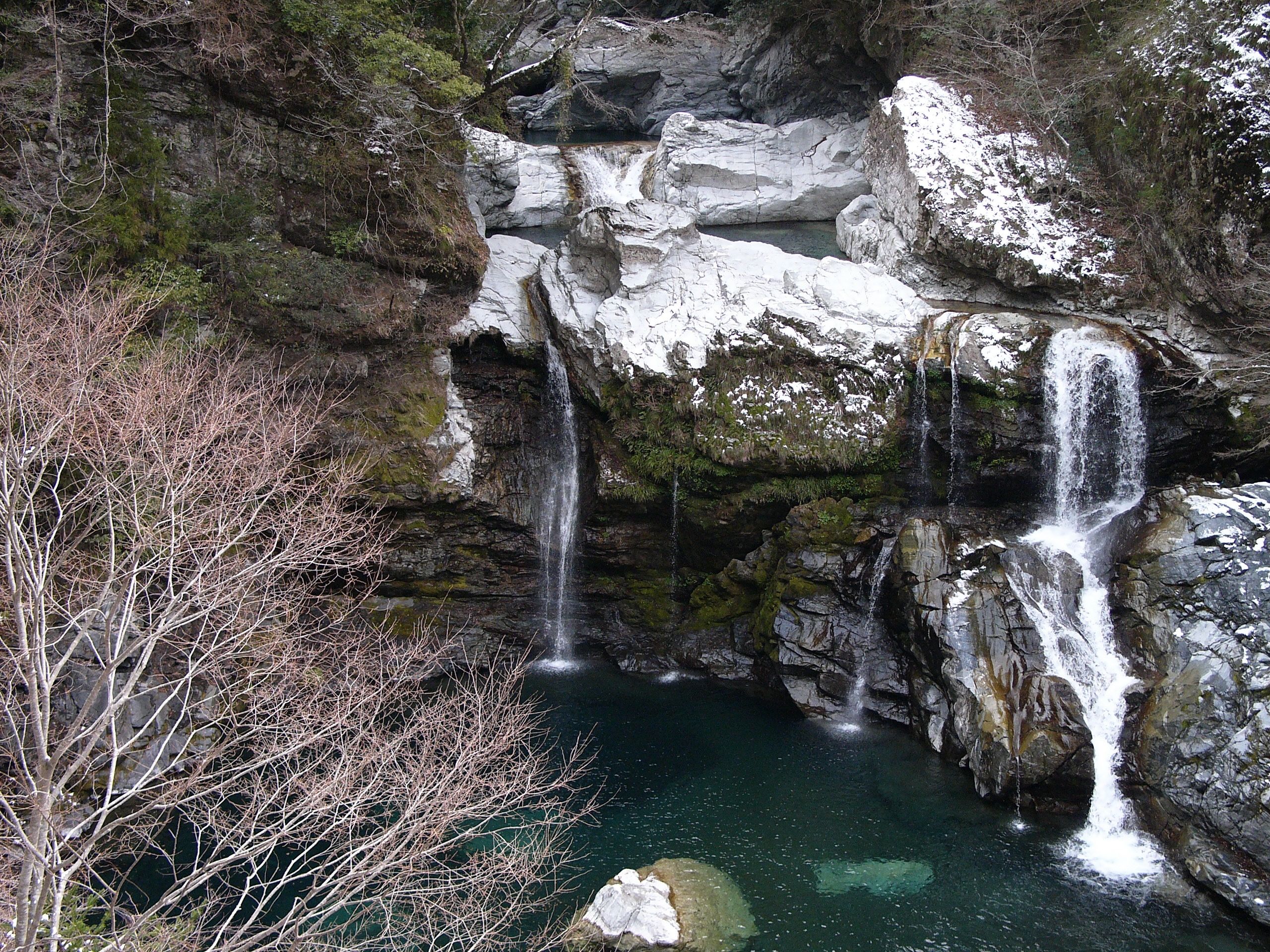 A small waterfall drops into a clear green lake.