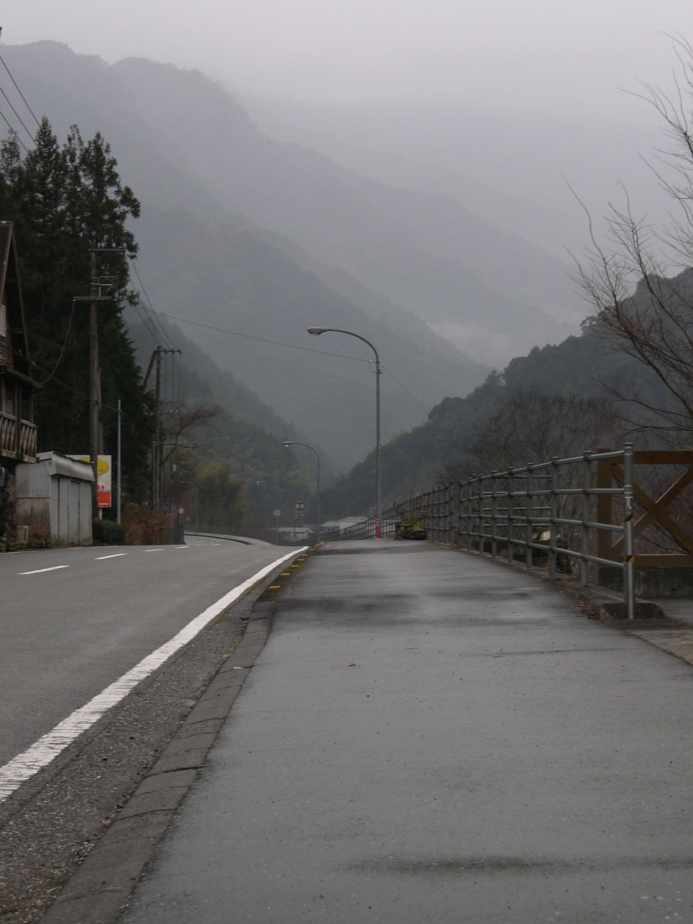 A pavement-level view of a valley overhung with low clouds.