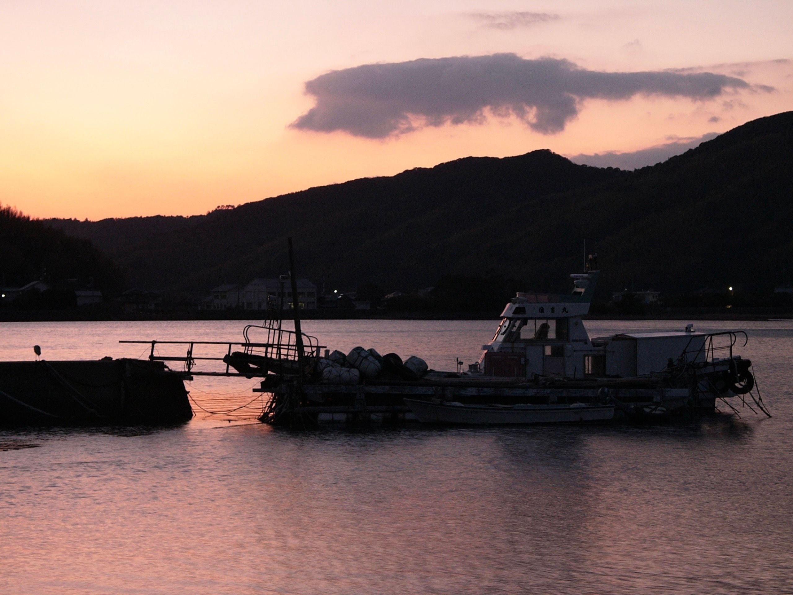 A small fishing boat in a harbor at dusk.