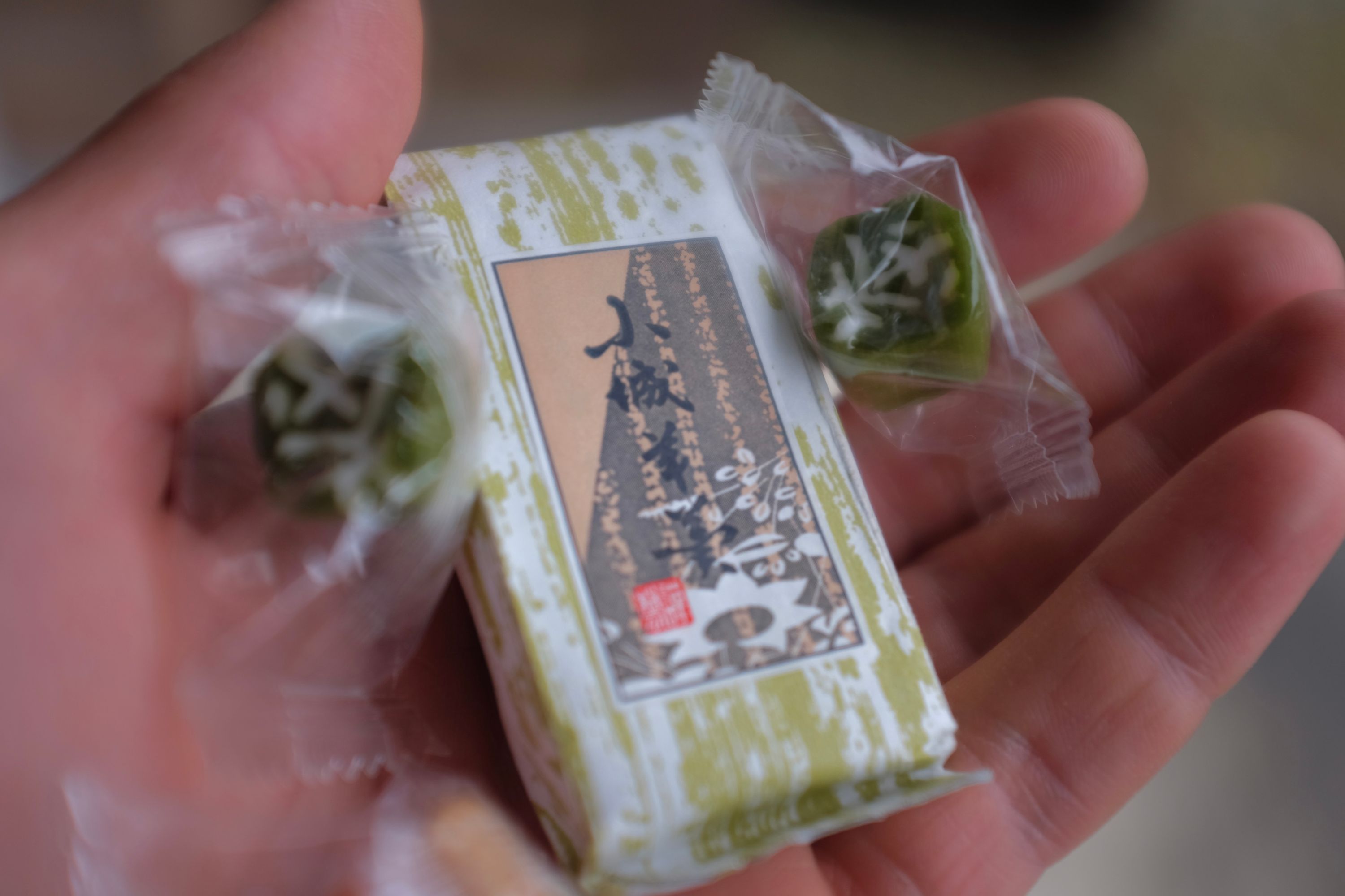 The author holds small packs of tea-flavored candy in his left hand.