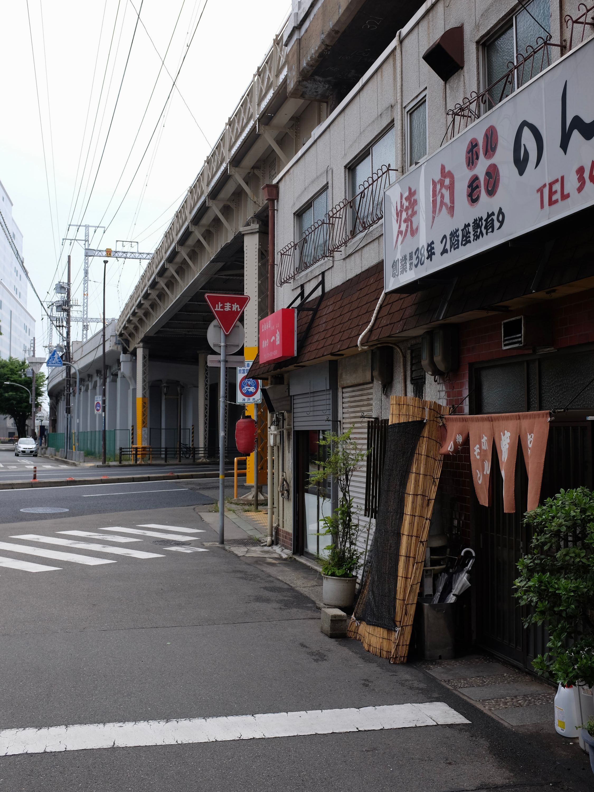 View along an elevated railway line with shops below it.