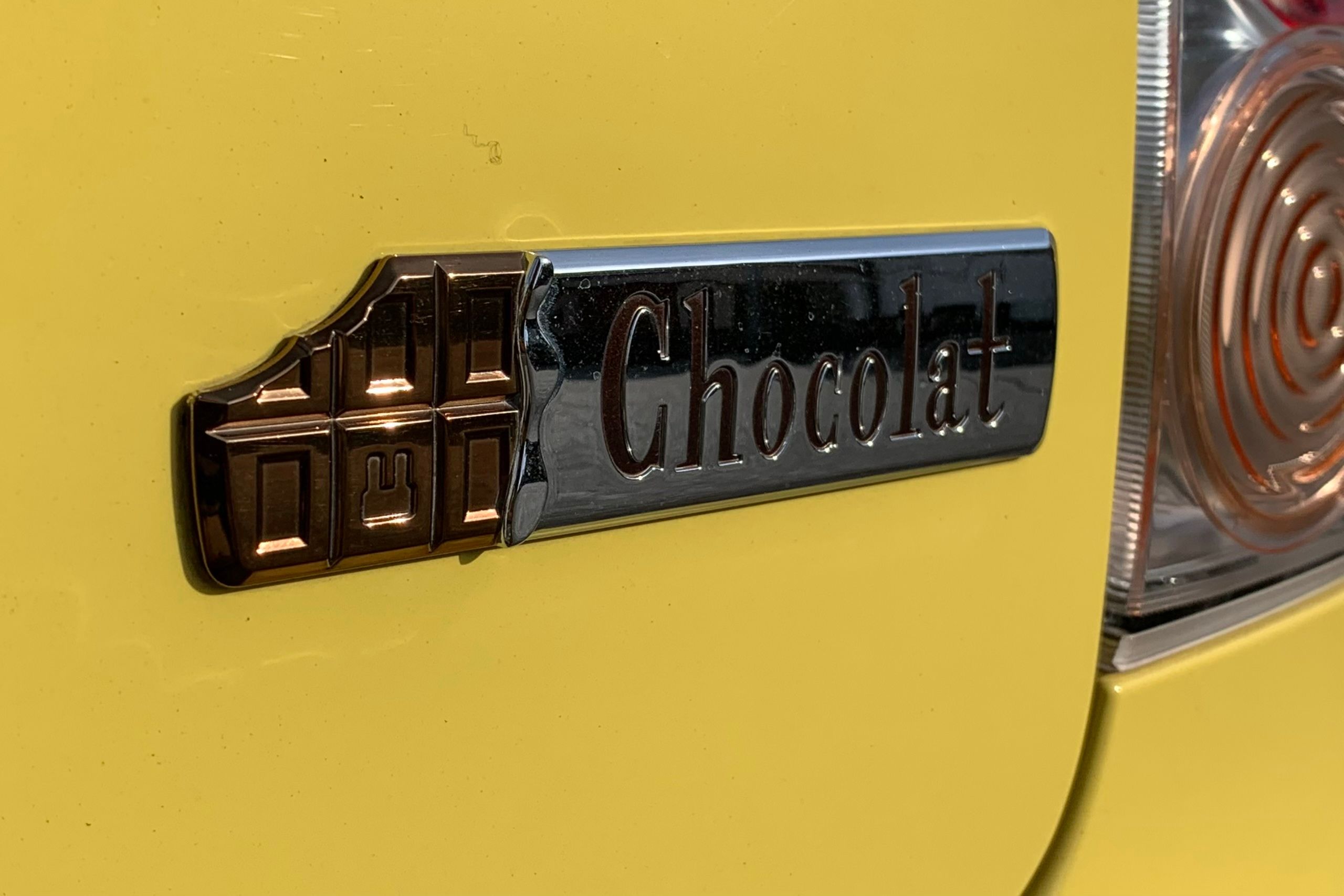 The emblem of the yellow car, a Lapin Chocolat, is a partially eaten chocolate bar with one of its squares stamped with the silhouelle of a rabbit.