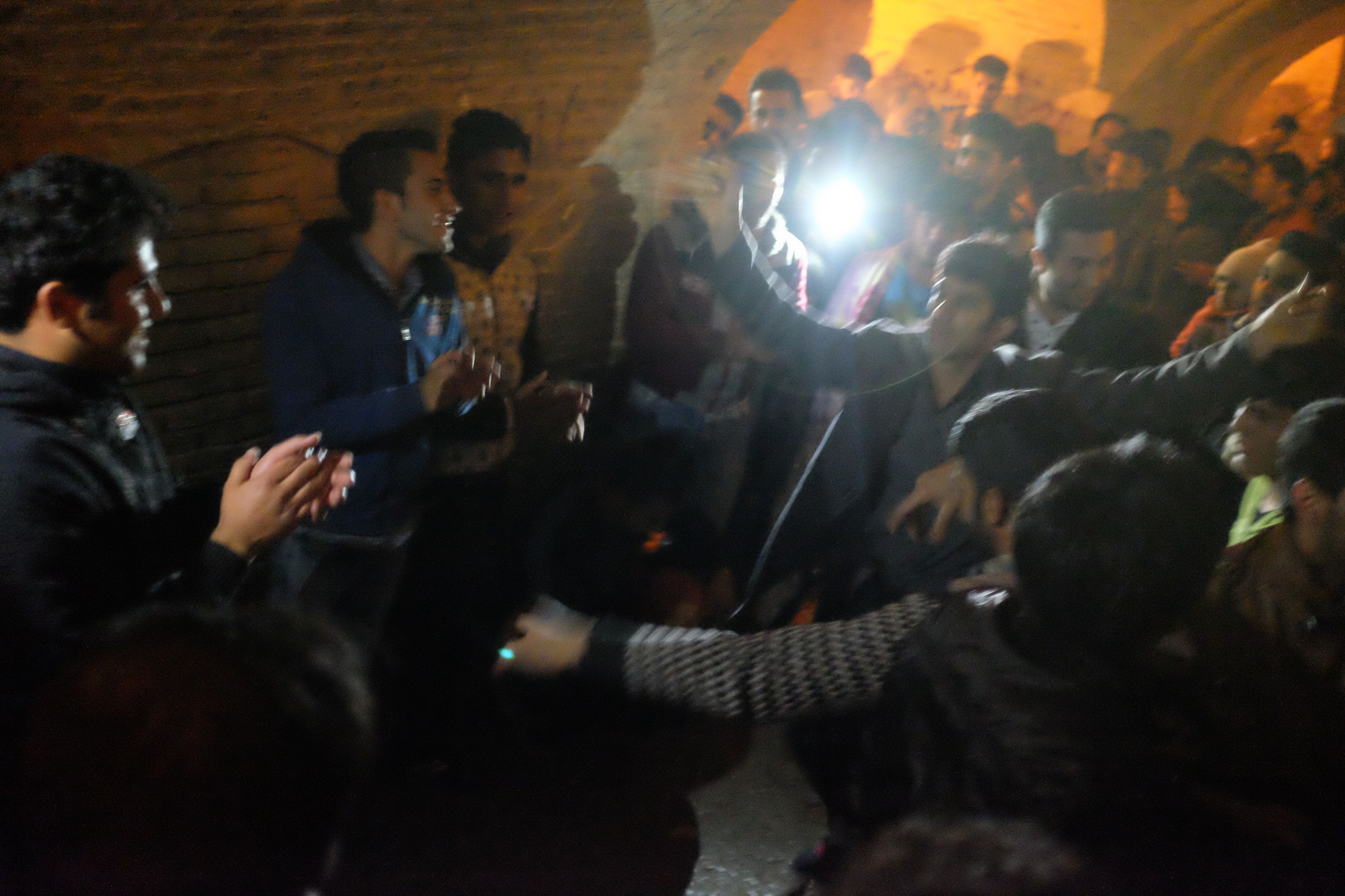 Young men dancing under a stone brige at night.