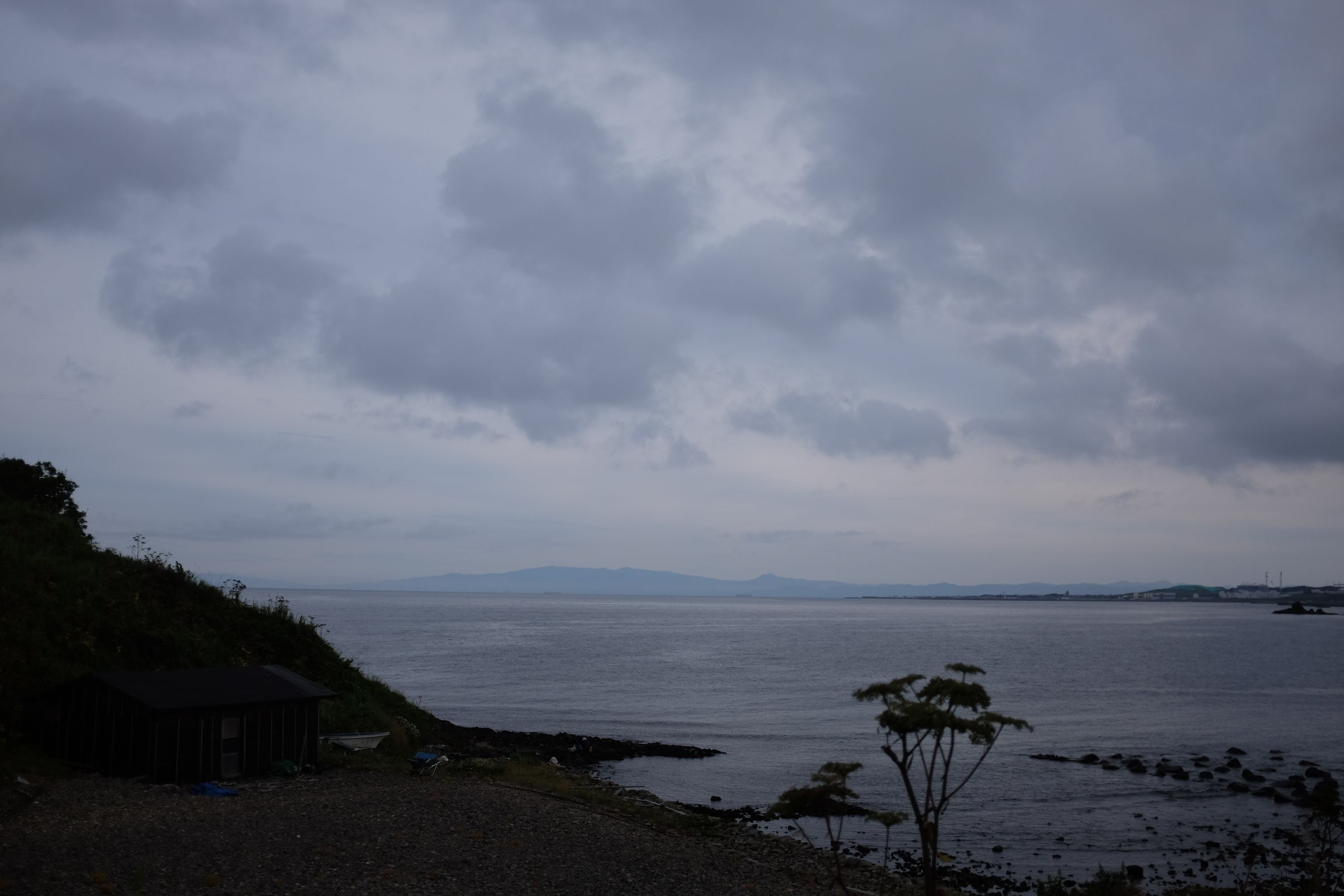 Across a grey seascape, the mountains of Hokkaido are visible.