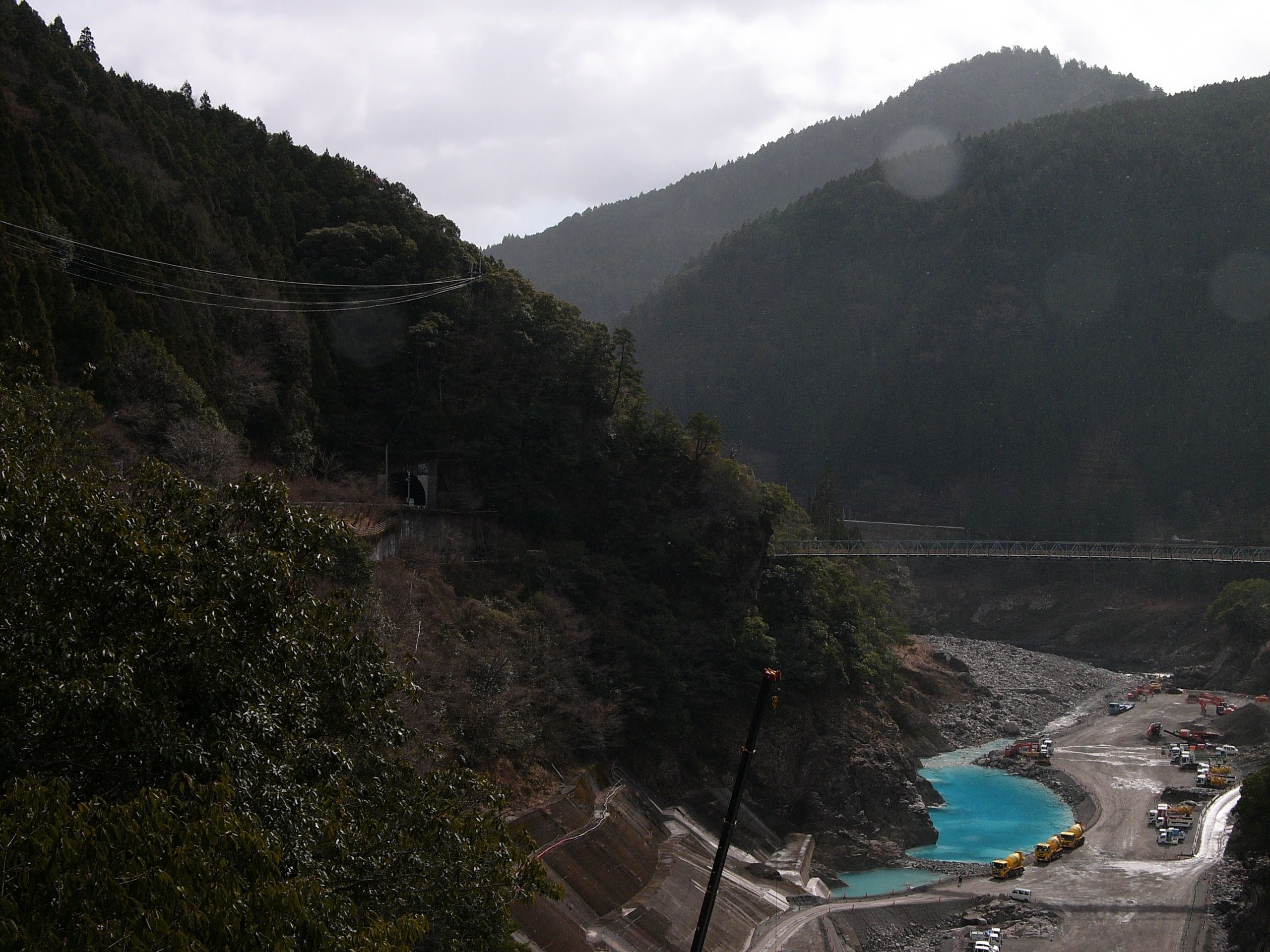 A blue lake downstream of a dam in a riverbed.