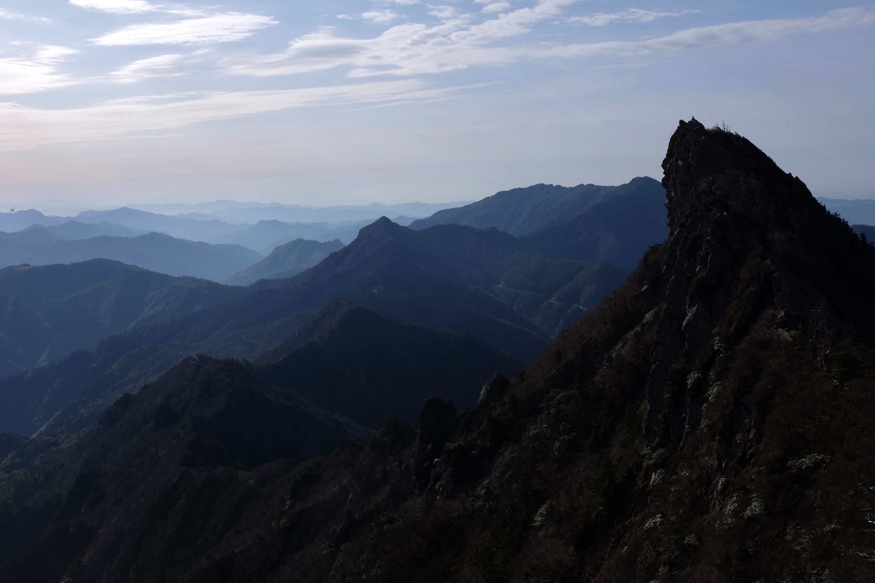 One of the two summits of Mount Ishizuchi with a sea of blue hills behind it.