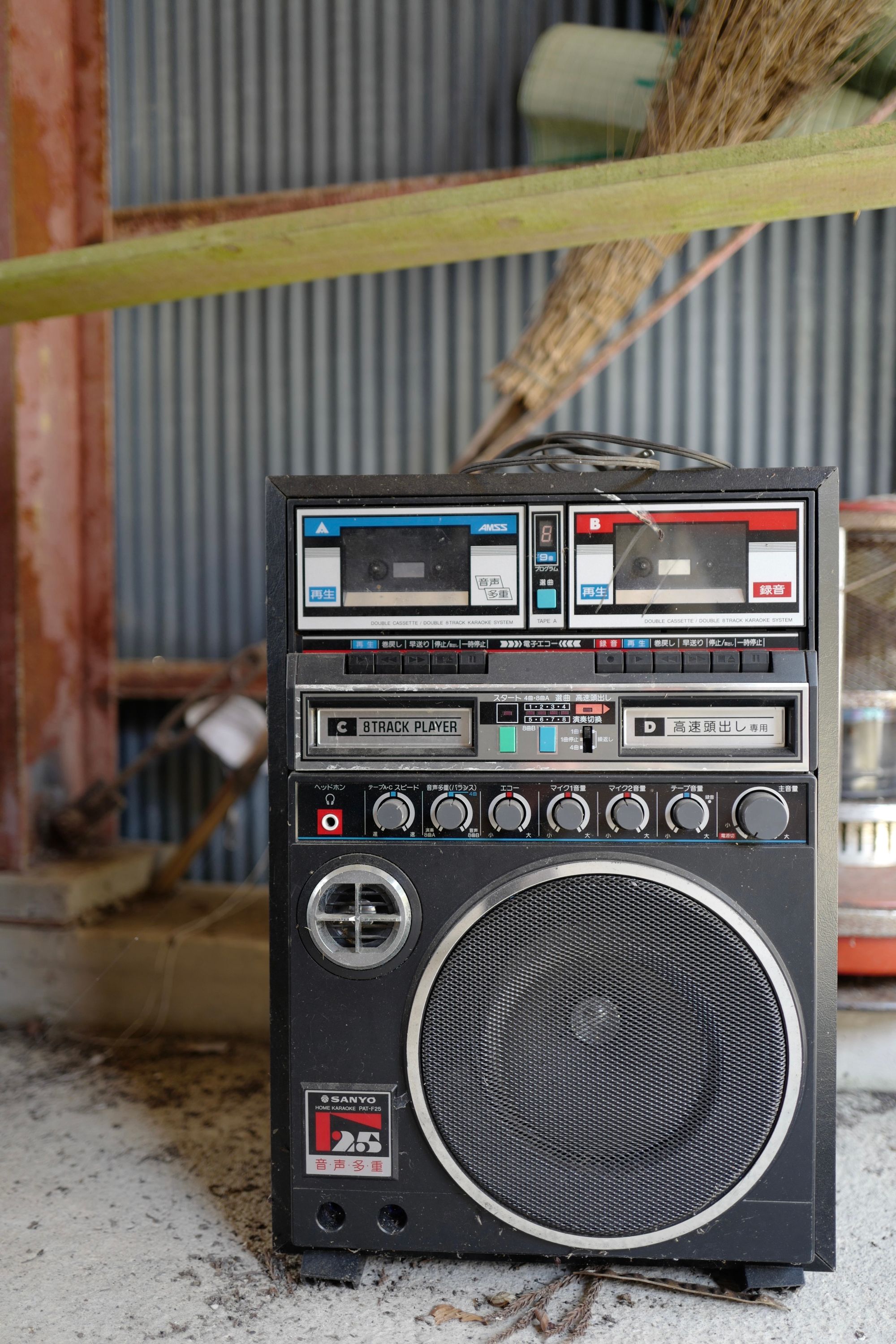 An 8-track player built into a larger speaker, in what appears to be a shed.