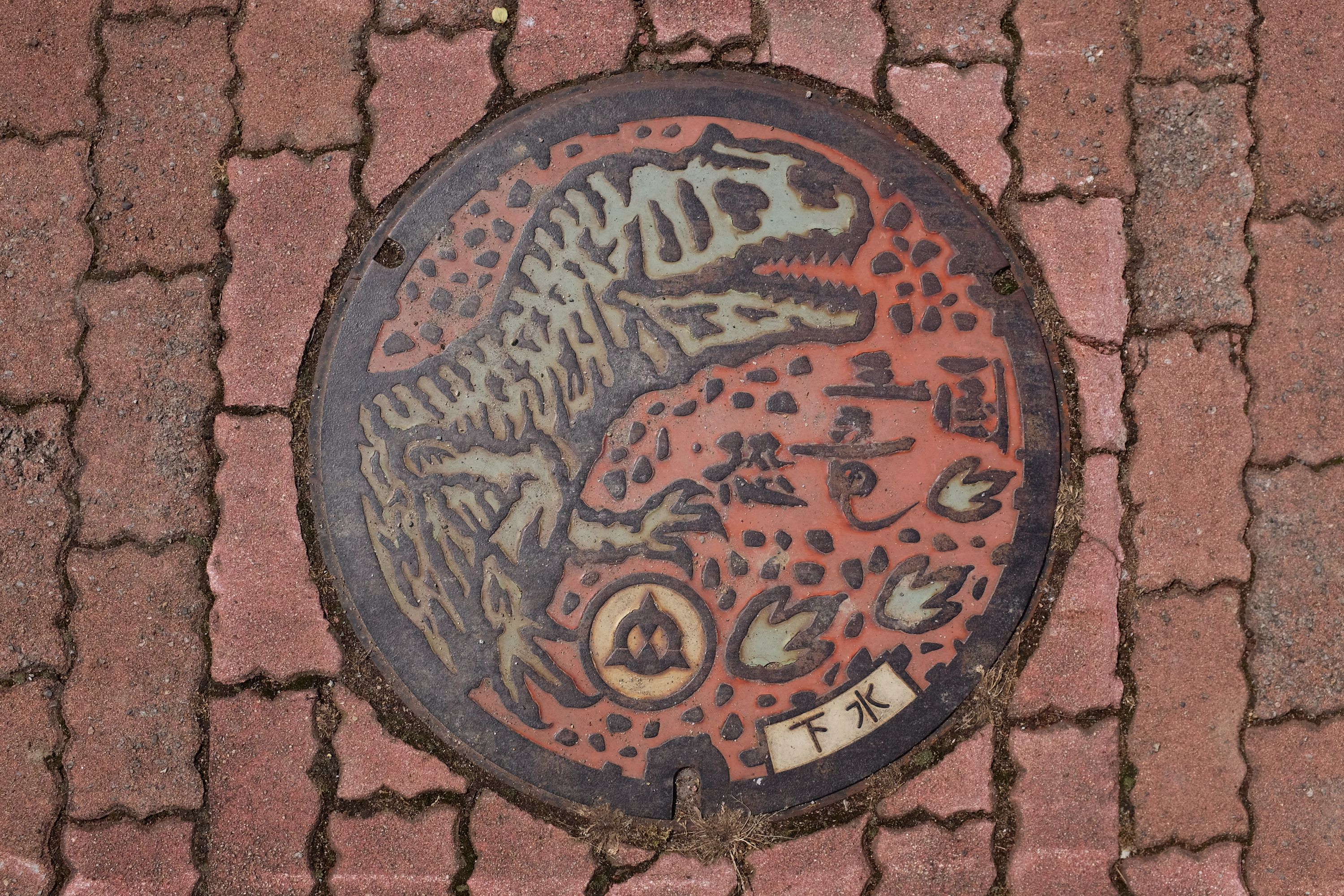 Manhole cover showing a theropod dinosaur.