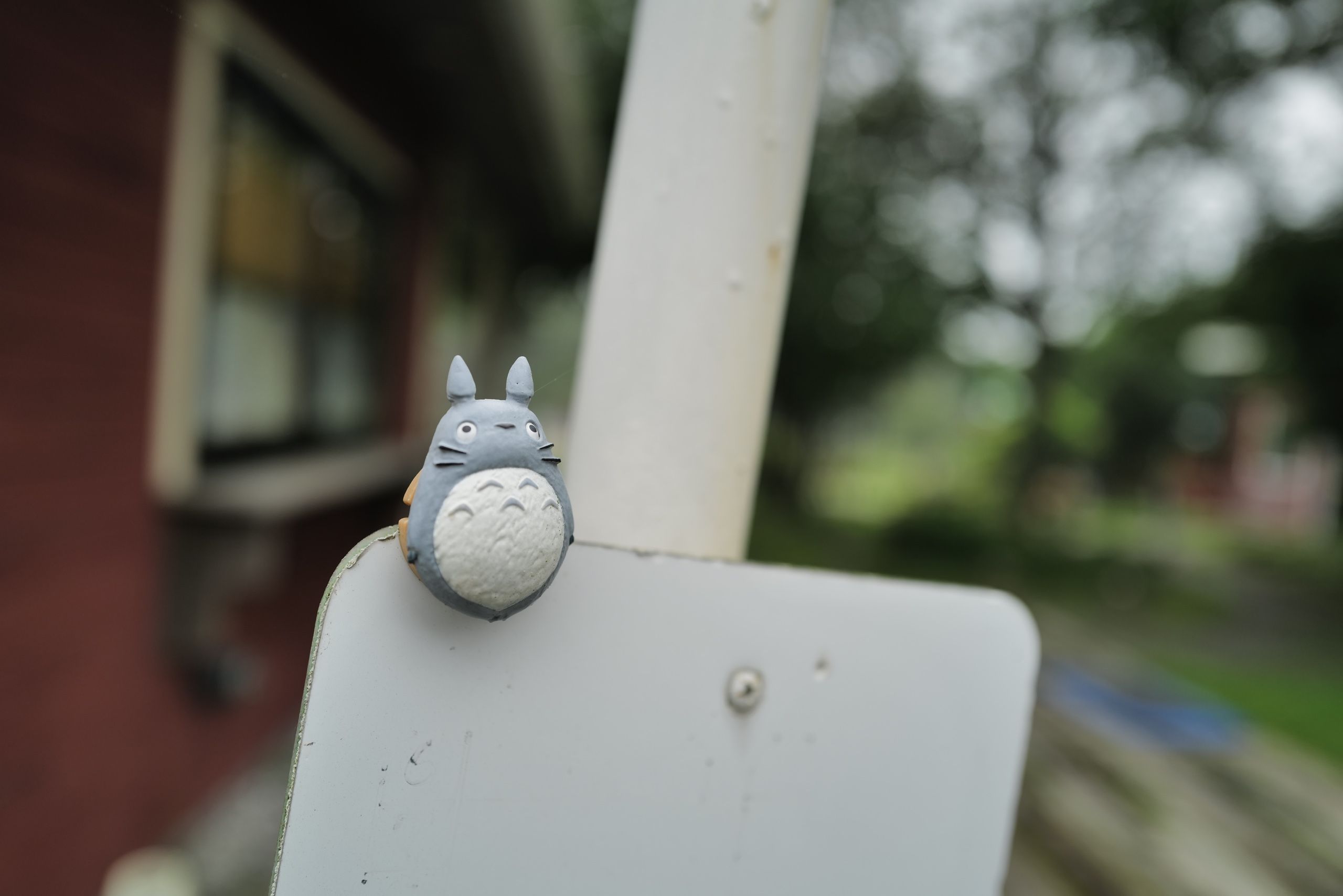 A small totoro perched on a blank sign.
