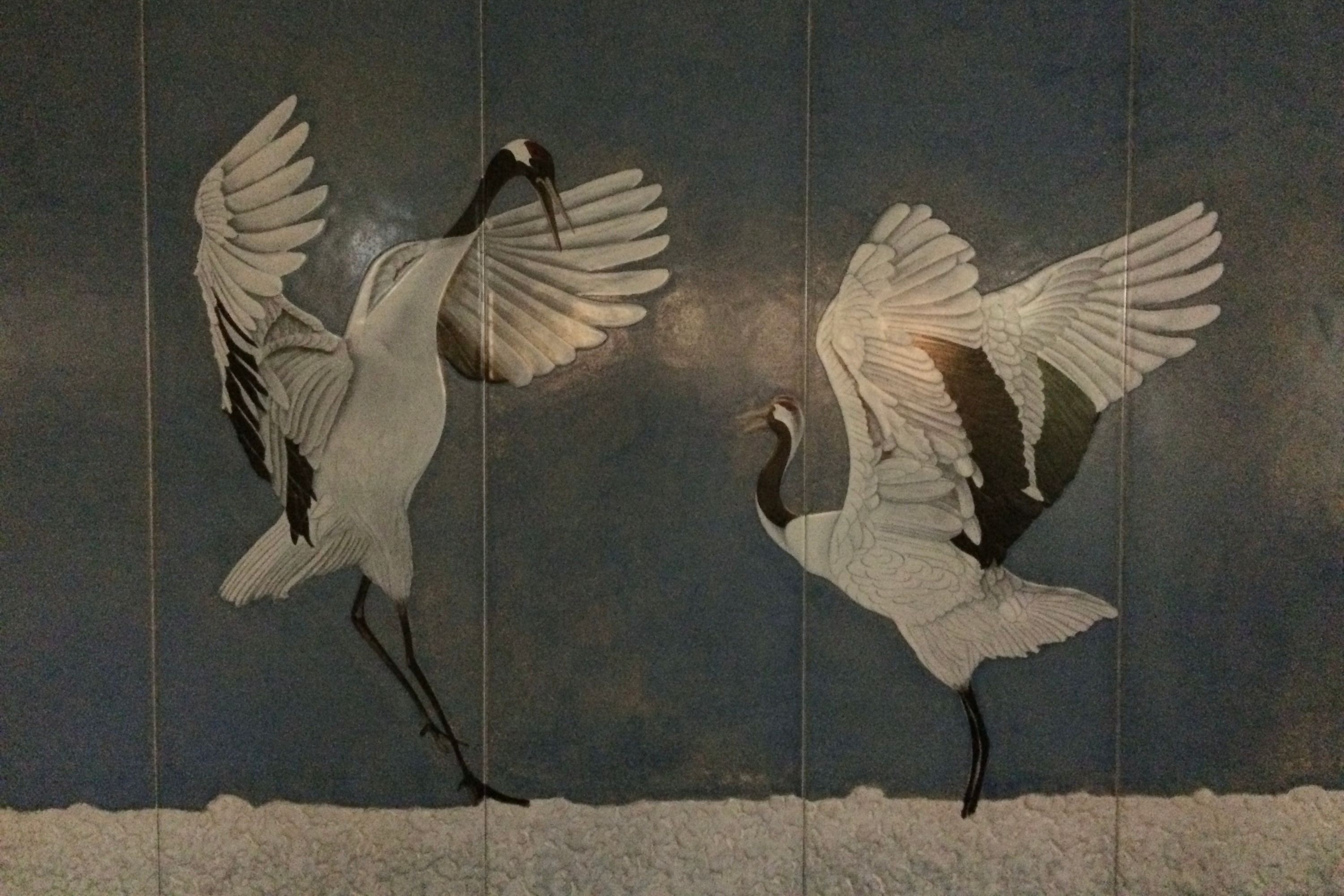 A mural of two red-crowned cranes dancing.