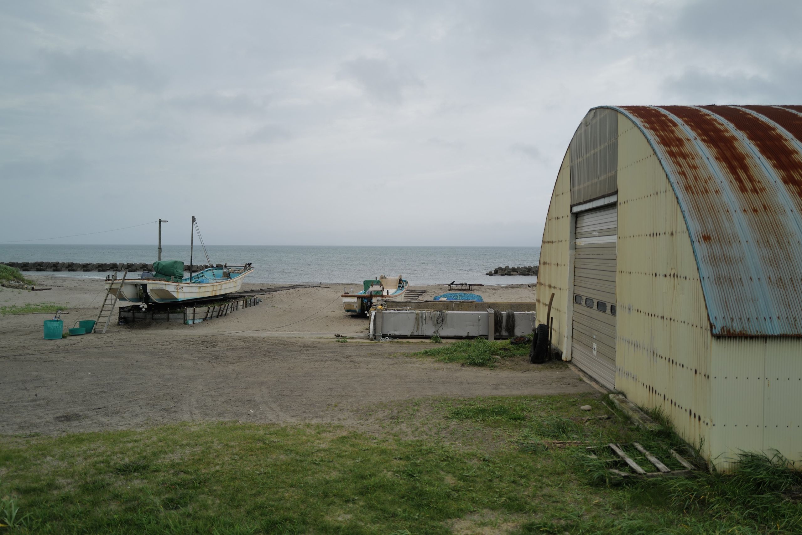 Fishing boats and a hangar on the shore in a village.