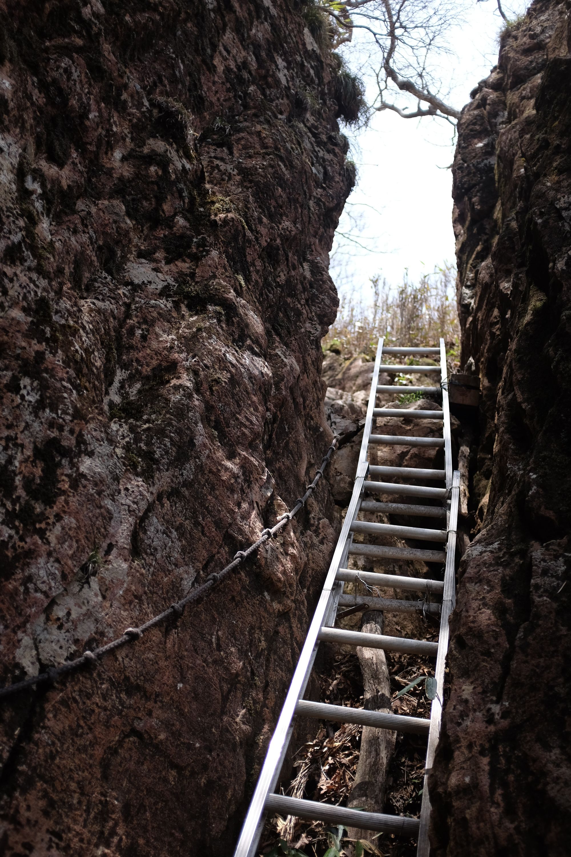 A ladder leads up in a cleft between two rocks.