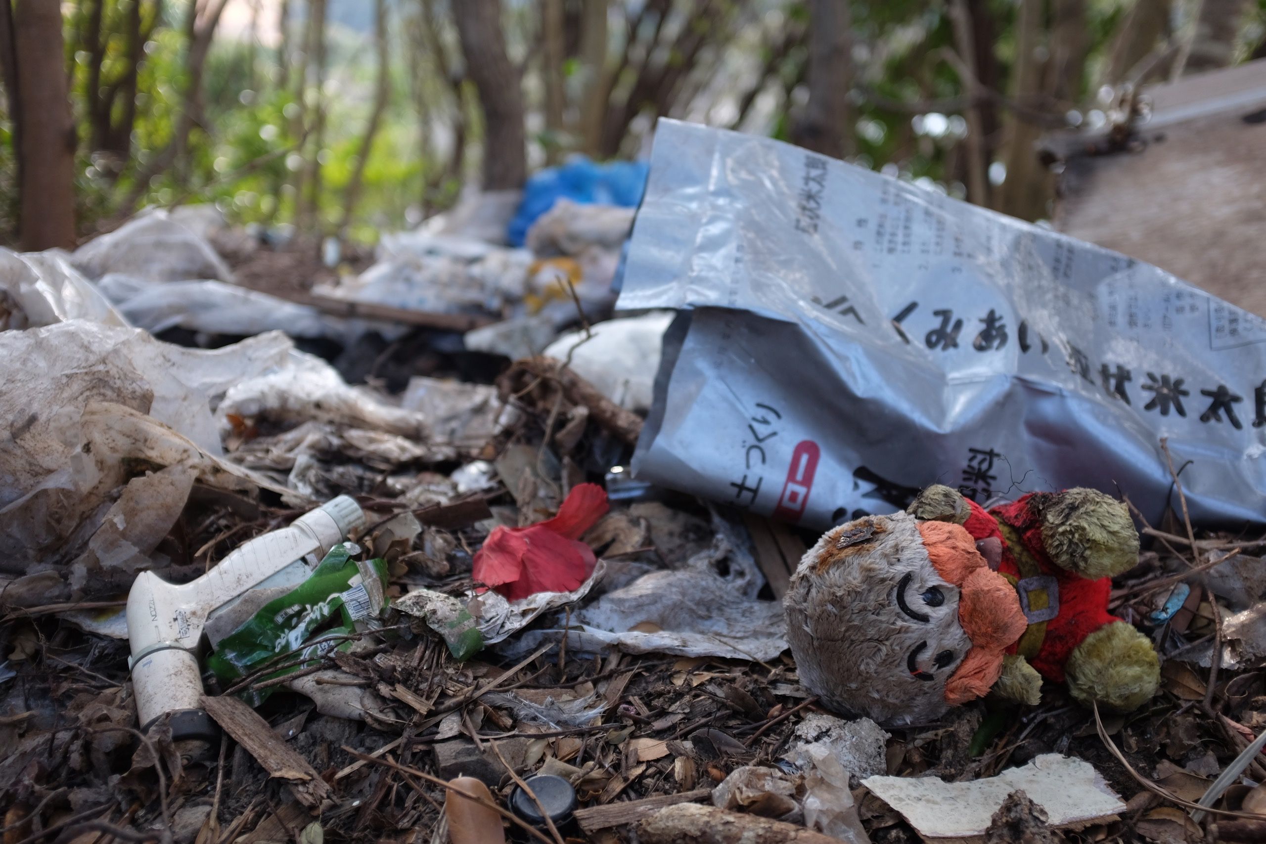 Toys and plastic waste on the ground in a forest.