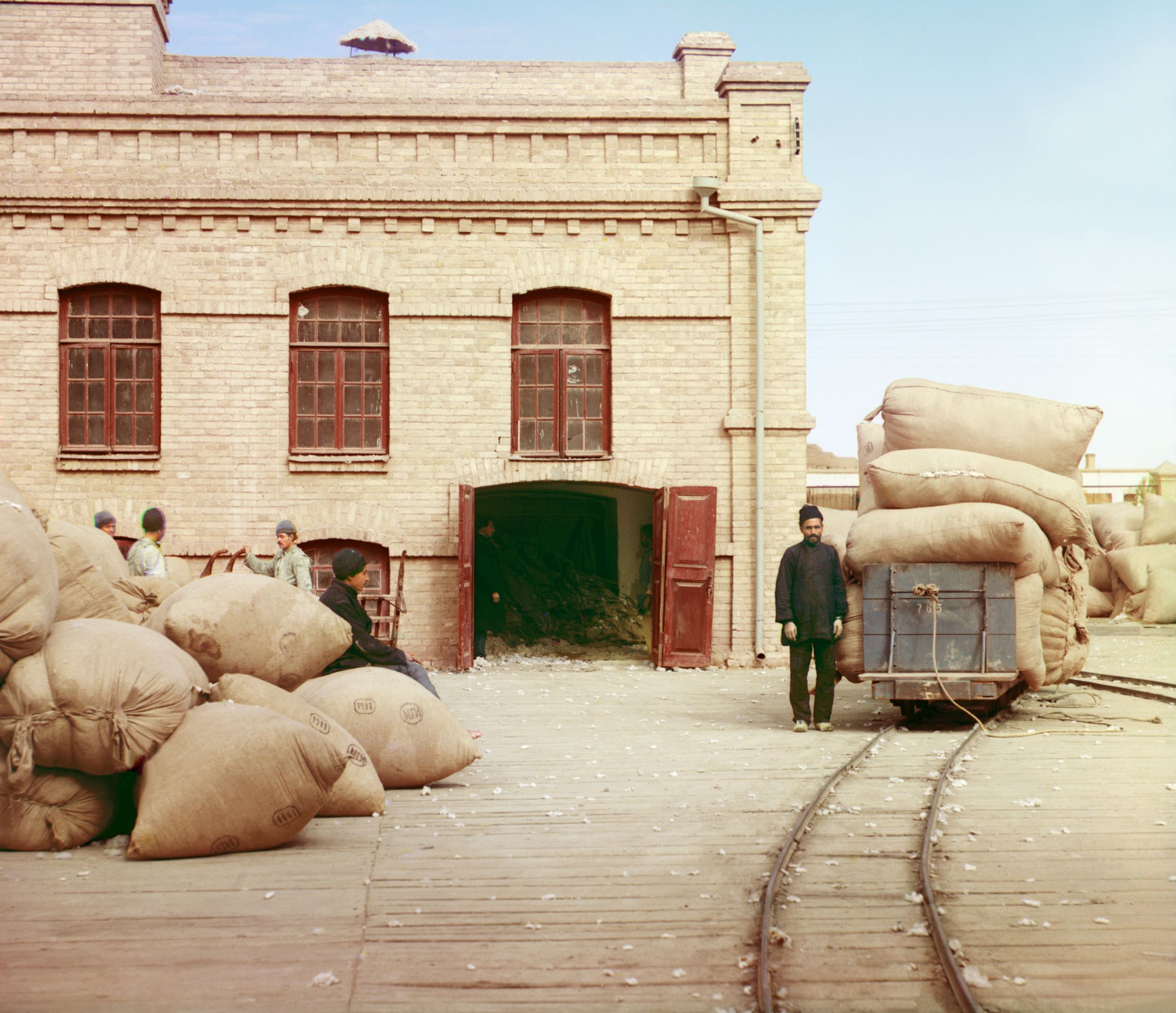 Laborers loading sacks onto railway at factory warehouse