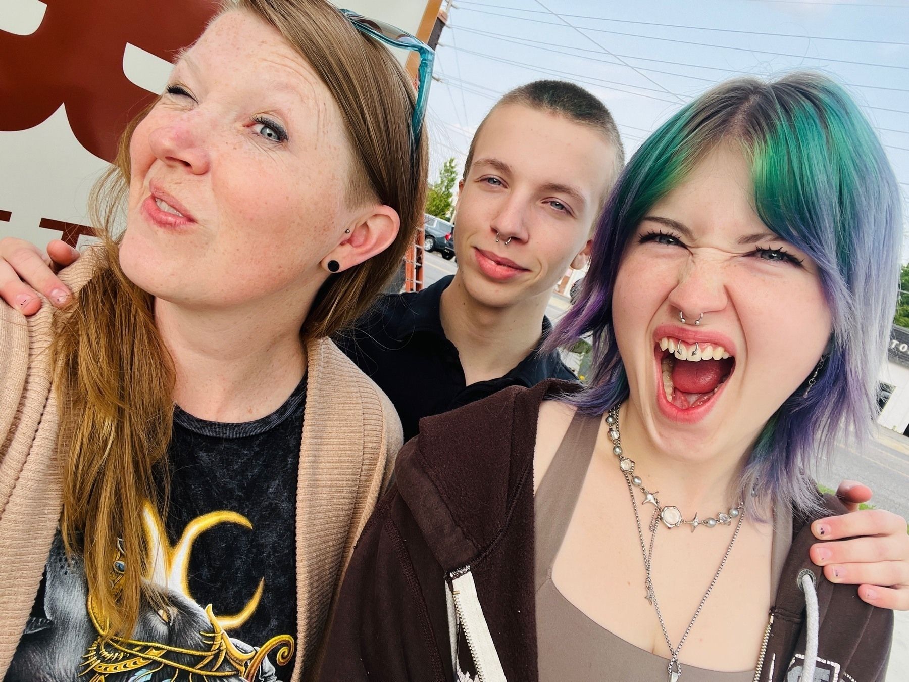 Mom with teenage daughter and teenage son making fierce faces at the camera with fresh piercings