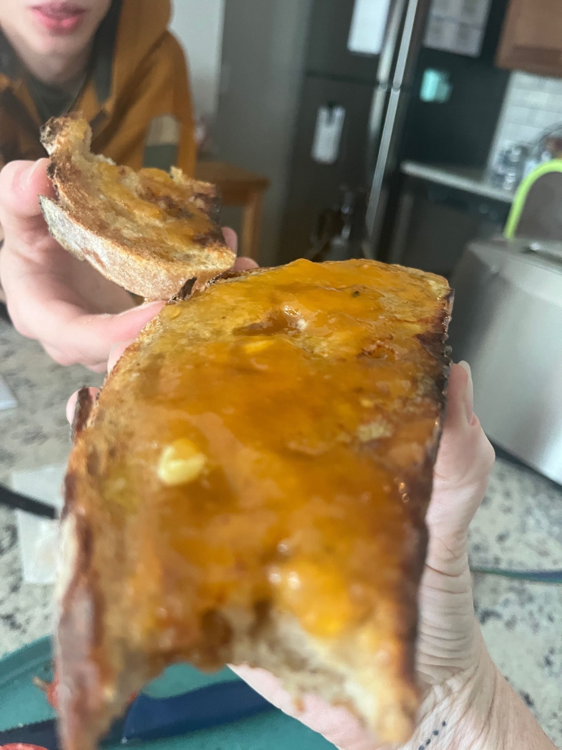 Thick slice of toasted sourdough bread smothered in peach buttercream held close to the camera