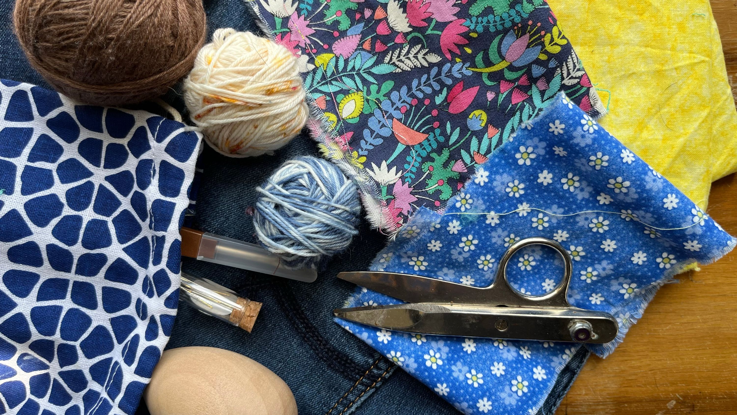 The mending kit that lives in the coffee table, with needles, yarn, fabric, a darning egg, and snips.