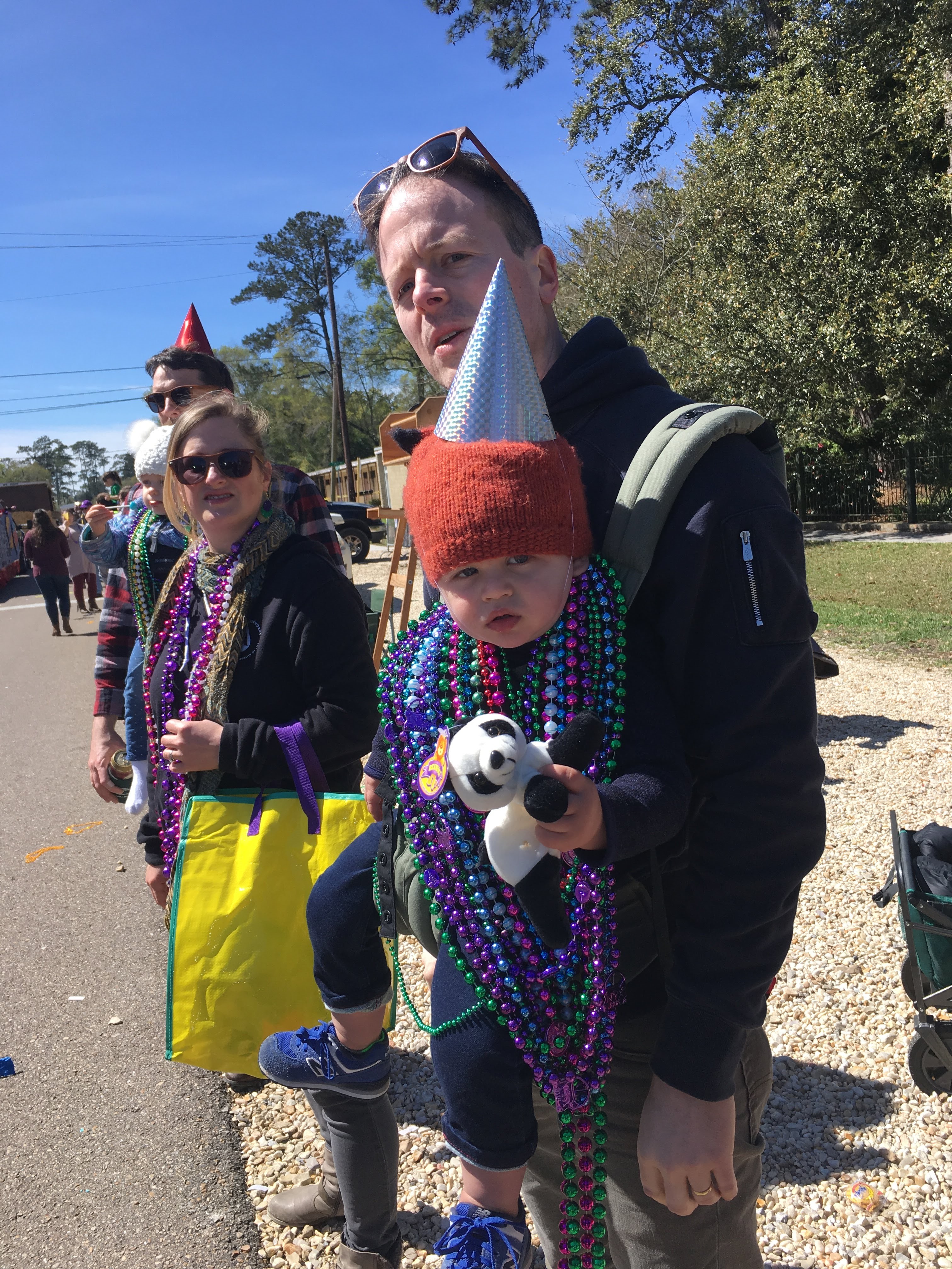 man carrying boy waiting for mardi gras floats