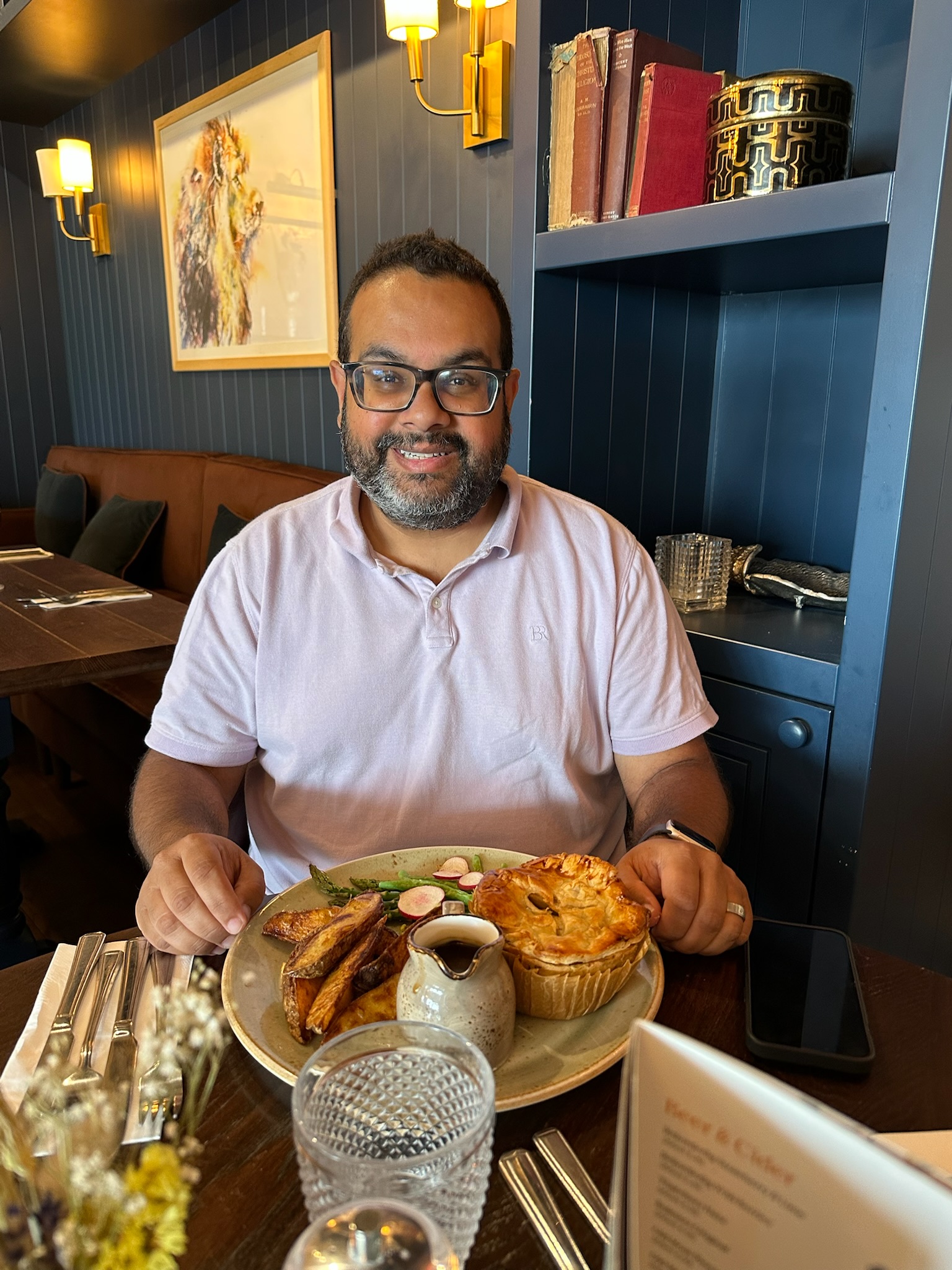 Sameer smiling at the table in front of a plate of food at the Wheatsheaf Inn